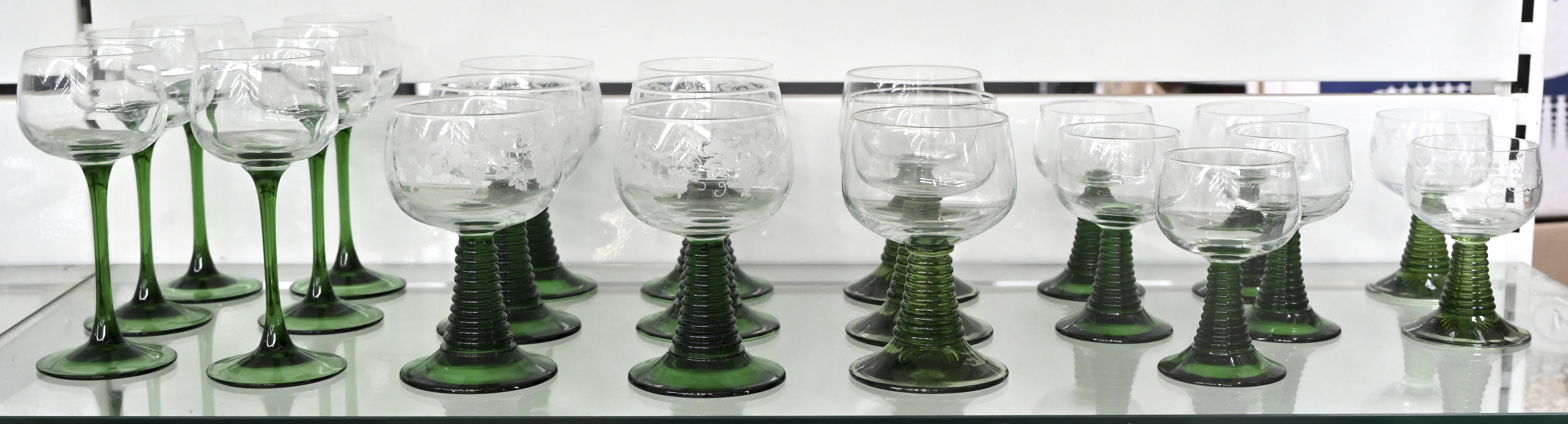 Zes wijnglazen op groene voet. Twaalf roemers met groene voet waarvan zes met wijnranken en vijf kleine roemers waarvan twee met wijnranken Zes wijnglazen op groene voet. Twaalf roemers met groene voet waarvan zes met wijnranken en vijf kleine roemers waarvan twee met wijnranken.