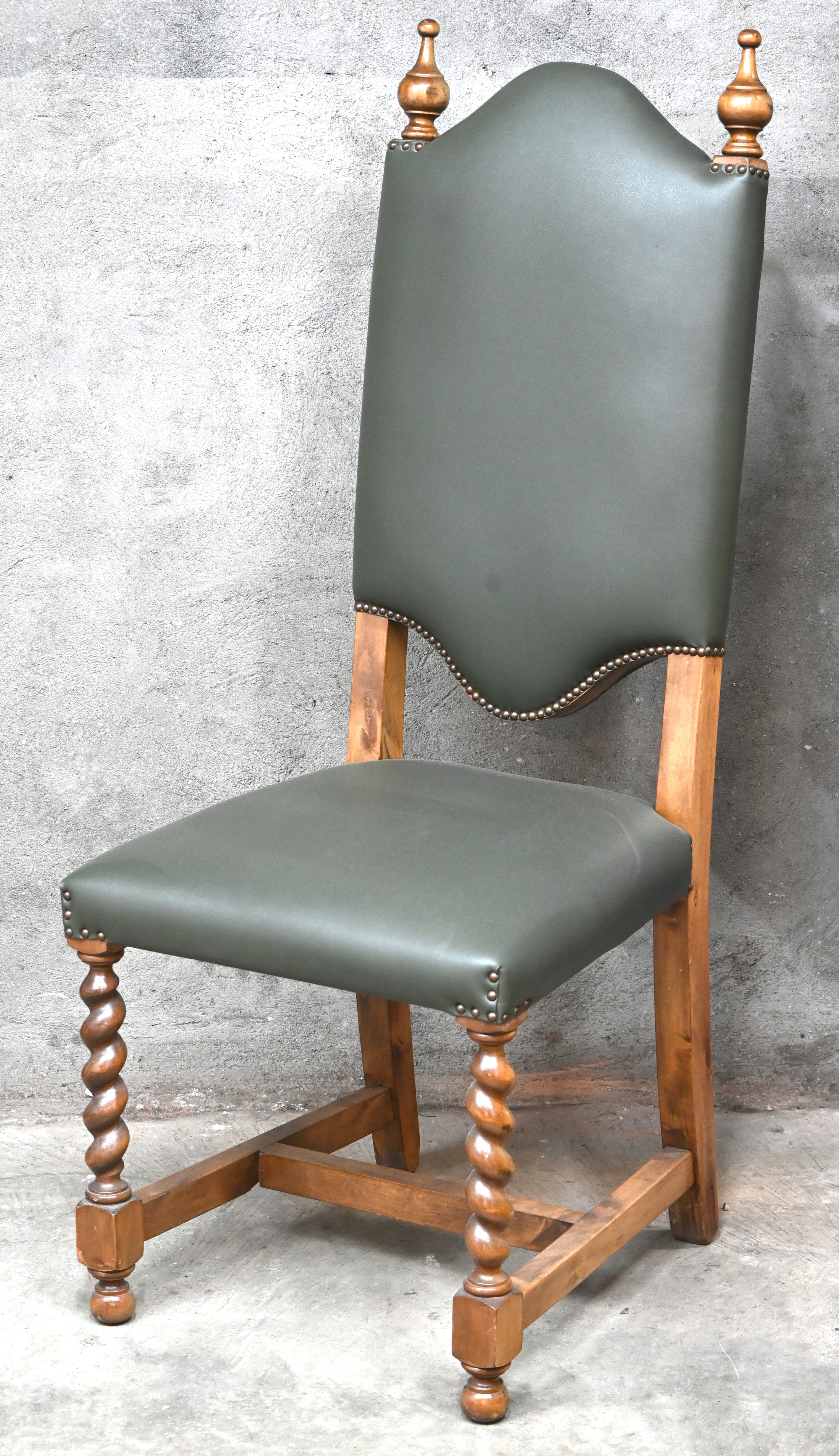 Een massief houten stoel met getorste poten en groene kunstlederen bekleding Een massief houten stoel met getorste poten en groene kunstlederen bekleding.