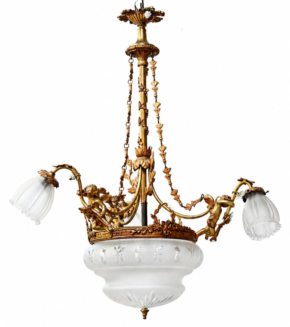 Een luchter van verguld brons met drie lichtpunten, glazen kapjes en een centrale coupe Een luchter van verguld brons met drie lichtpunten, glazen kapjes en een centrale coupe.