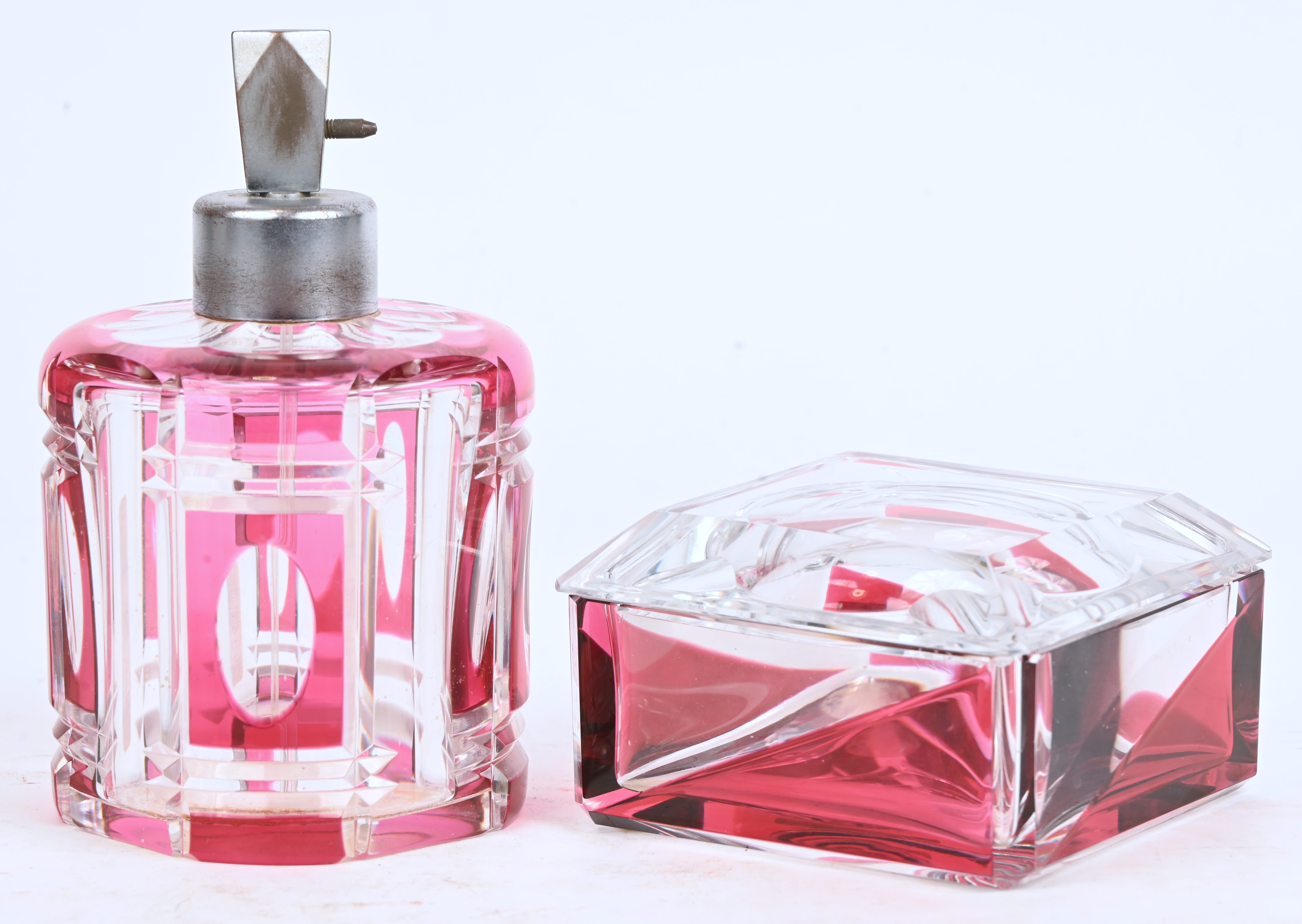 Een kristallen parfumflacon en asbak/dekselpot, roze in de massa gekleurd, onderaan gemerkt Een kristallen parfumflacon en asbak/dekselpot, roze in de massa gekleurd, onderaan gemerkt.