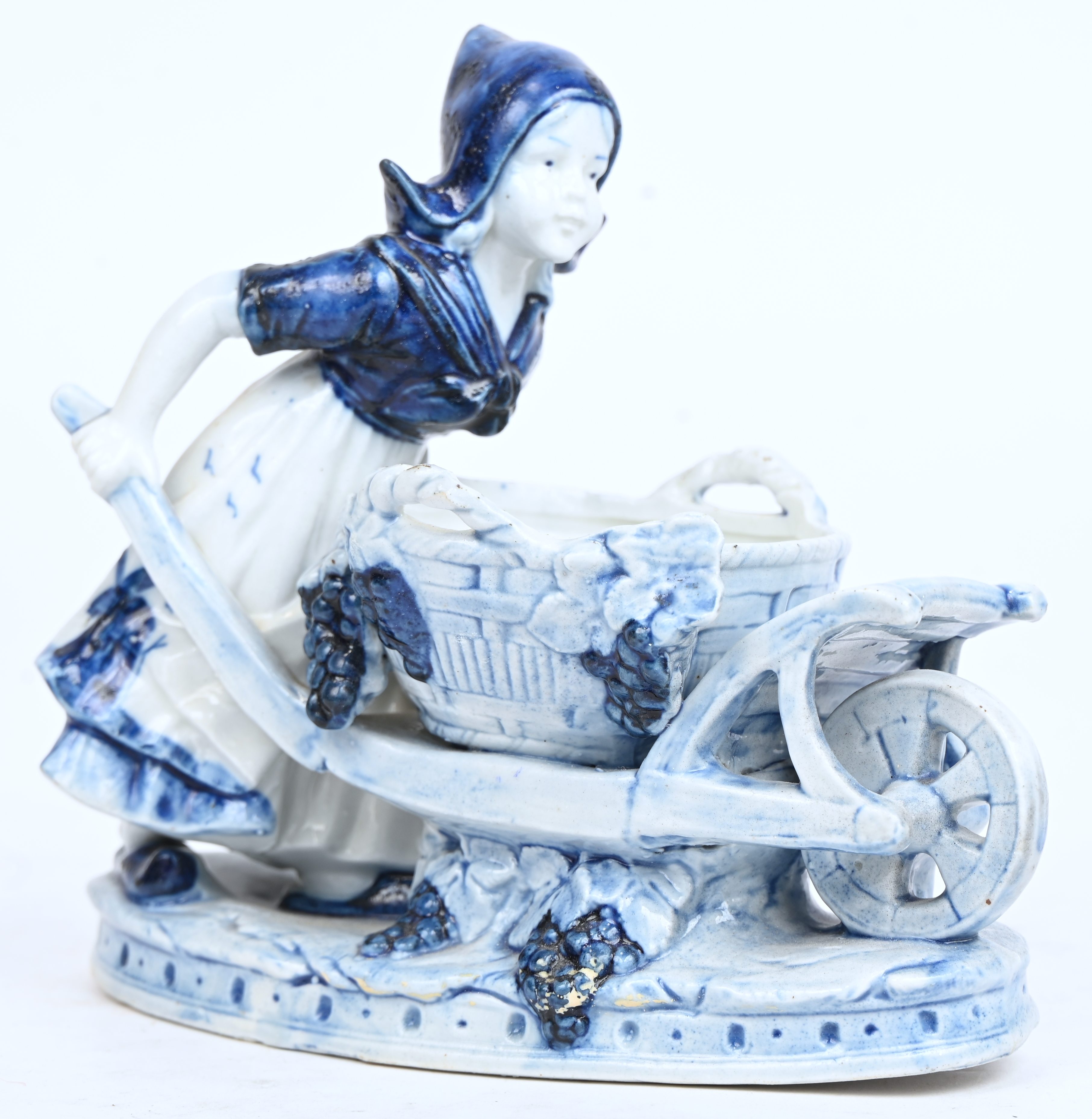 Een beeldje van een jong meisje met kar, Delfts blauw aardewerk Een beeldje van een jong meisje met kar, Delfts blauw aardewerk.
