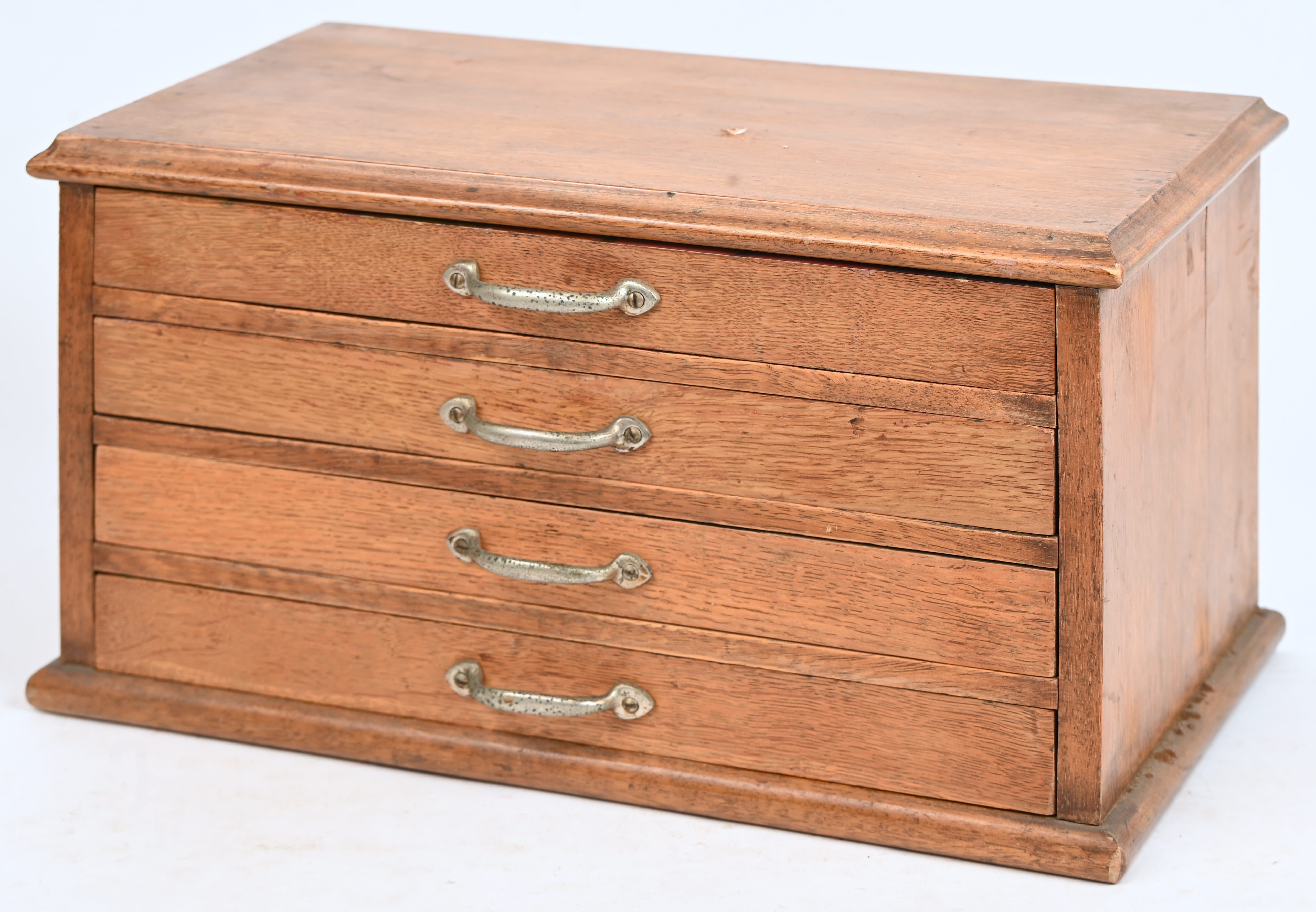 Een klein houten ladenkastje. Met vier laden, in de lengte verdeeld in compartimenten Een klein houten ladenkastje. Met vier laden, in de lengte verdeeld in compartimenten.