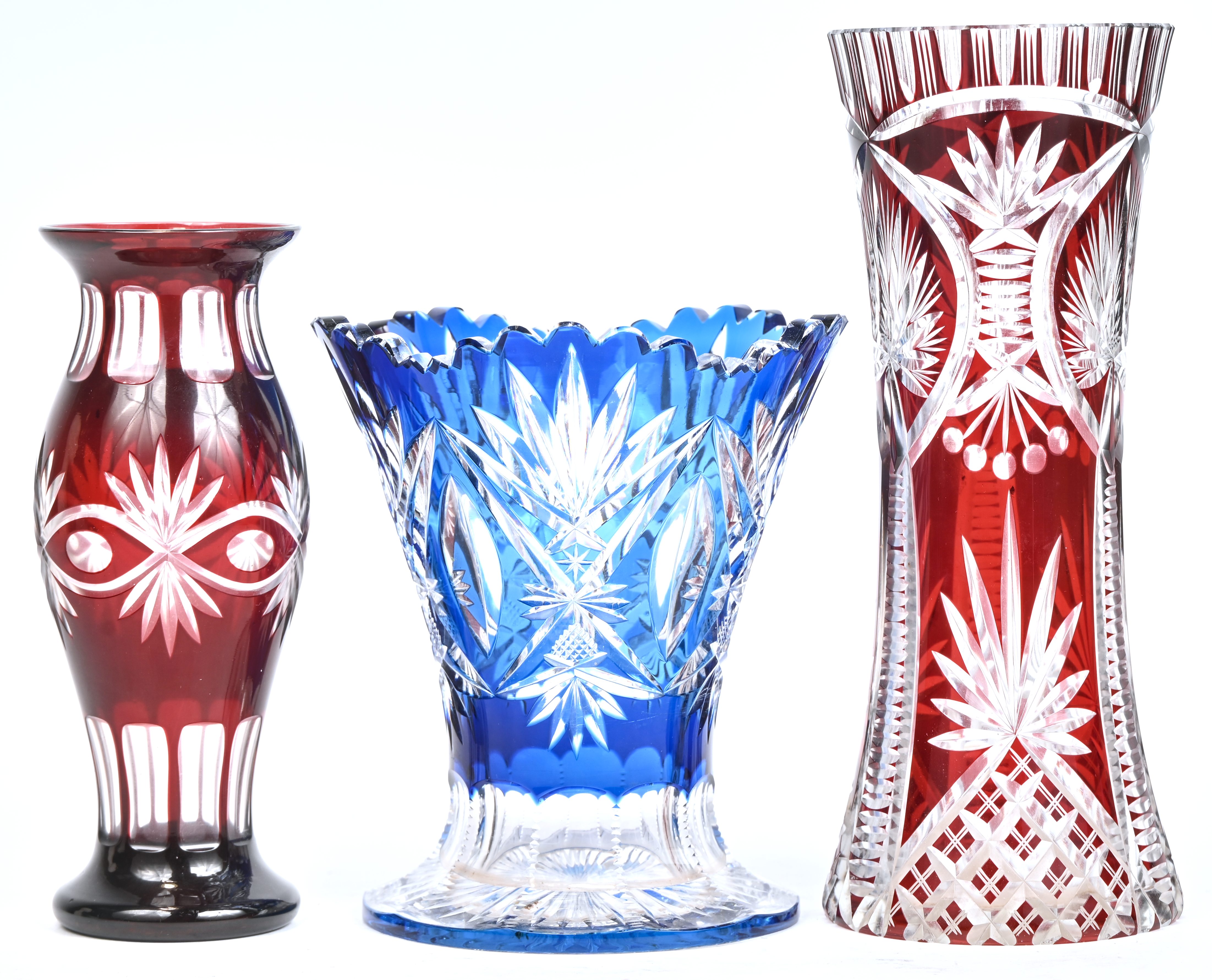 Drie vazen waarvan twee Boheems kristal en één glas. De blauwe vaas heeft schilferschade aan de rand en basis Drie vazen waarvan twee Boheems kristal en één glas. De blauwe vaas heeft schilferschade aan de rand en basis.