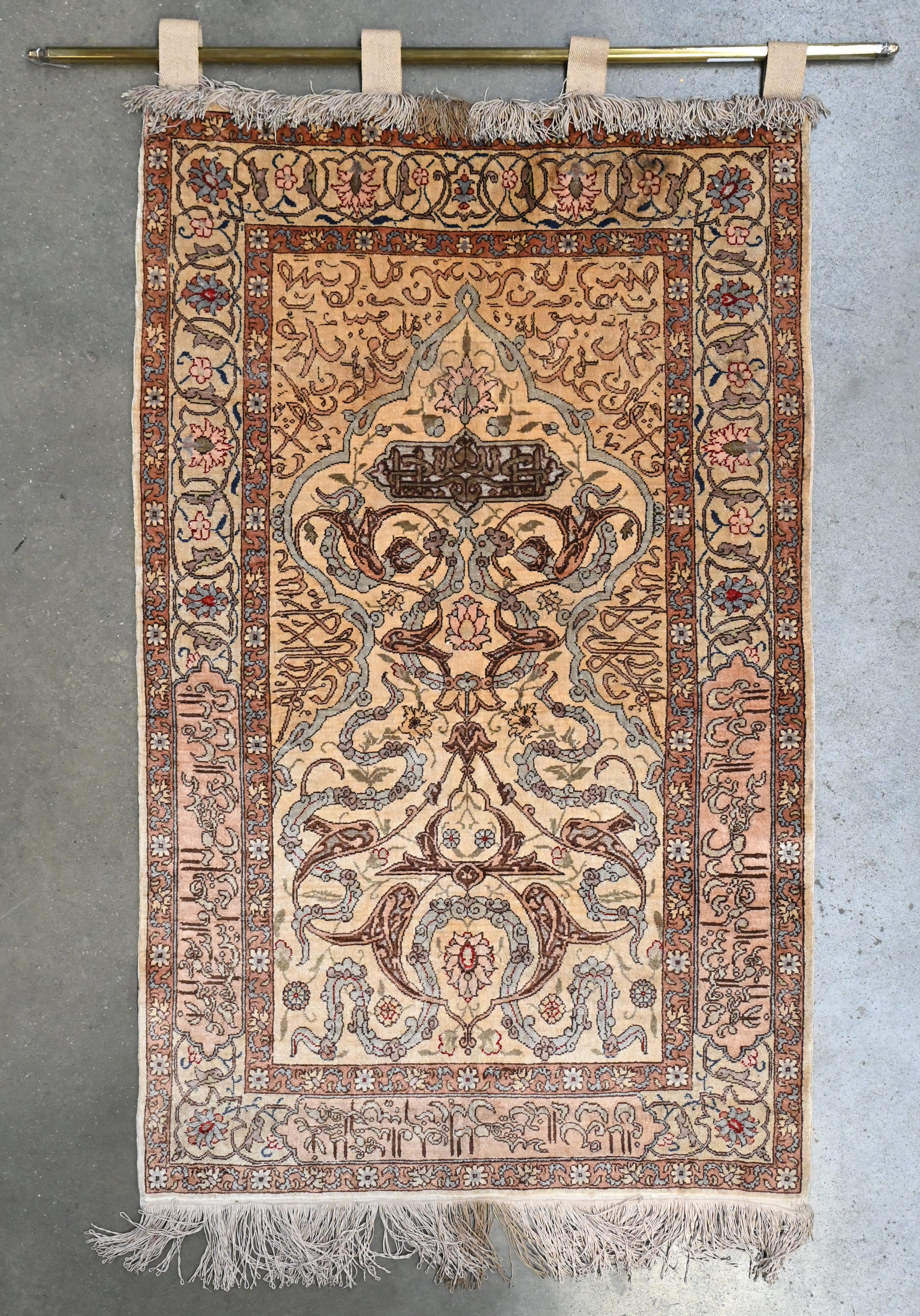 Een Perzische zijden bidmat, gemonteerd als wandtapijtje. Met florale en kalligrafische decoratie Een Perzische zijden bidmat, gemonteerd als wandtapijtje. Met florale en kalligrafische decoratie.