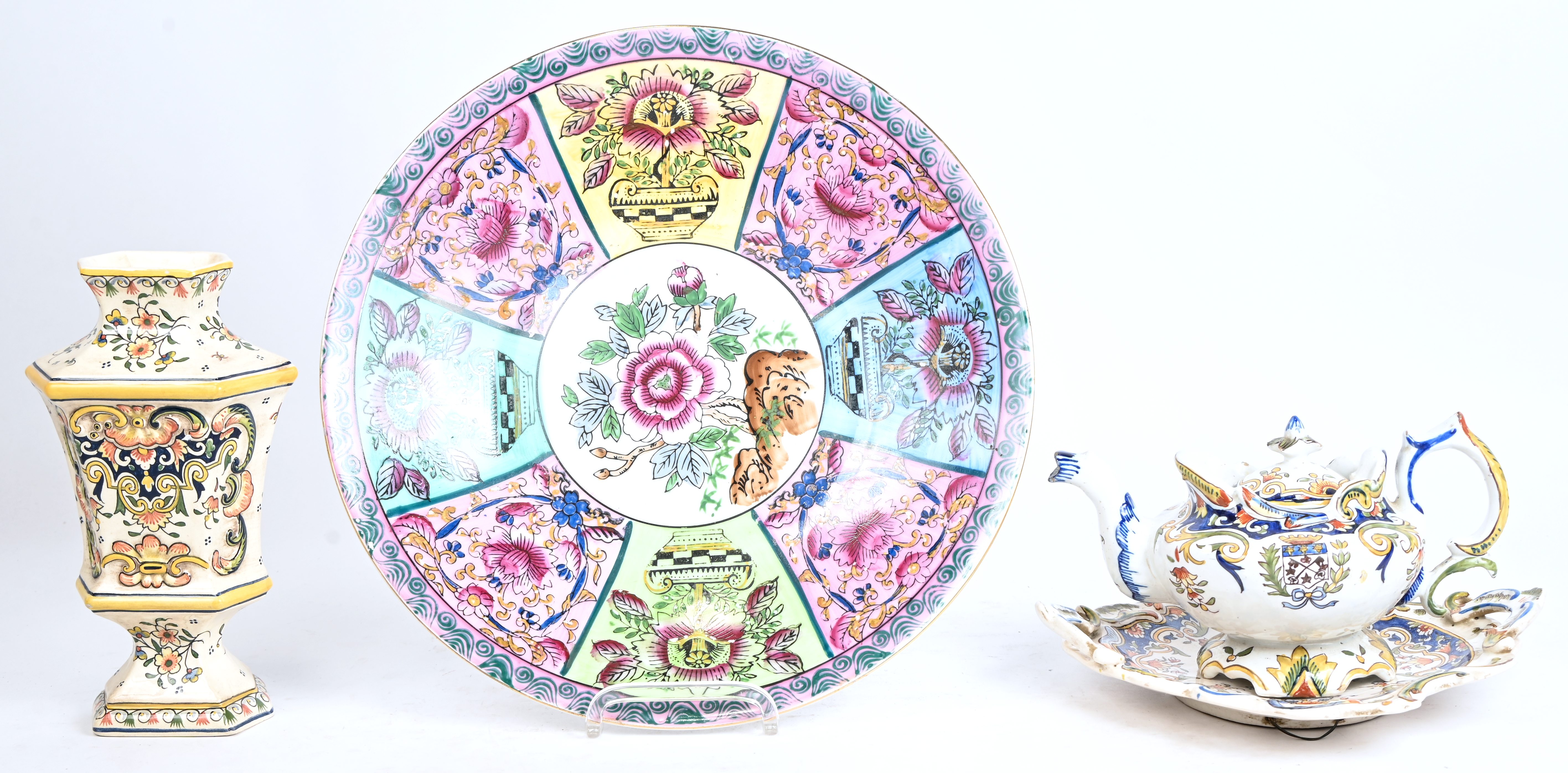 Een gevarieerd lot meerkleurig aardewerk. Omvat een grote sierschotel famille rose, een Rouen vaas en een decoratief theepotje met bijhorende schotel, gemerkt Lisieux Een gevarieerd lot meerkleurig aardewerk. Omvat een grote sierschotel famille rose, een Rouen vaas en een decoratief theepotje met bijhorende schotel, gemerkt Lisieux.