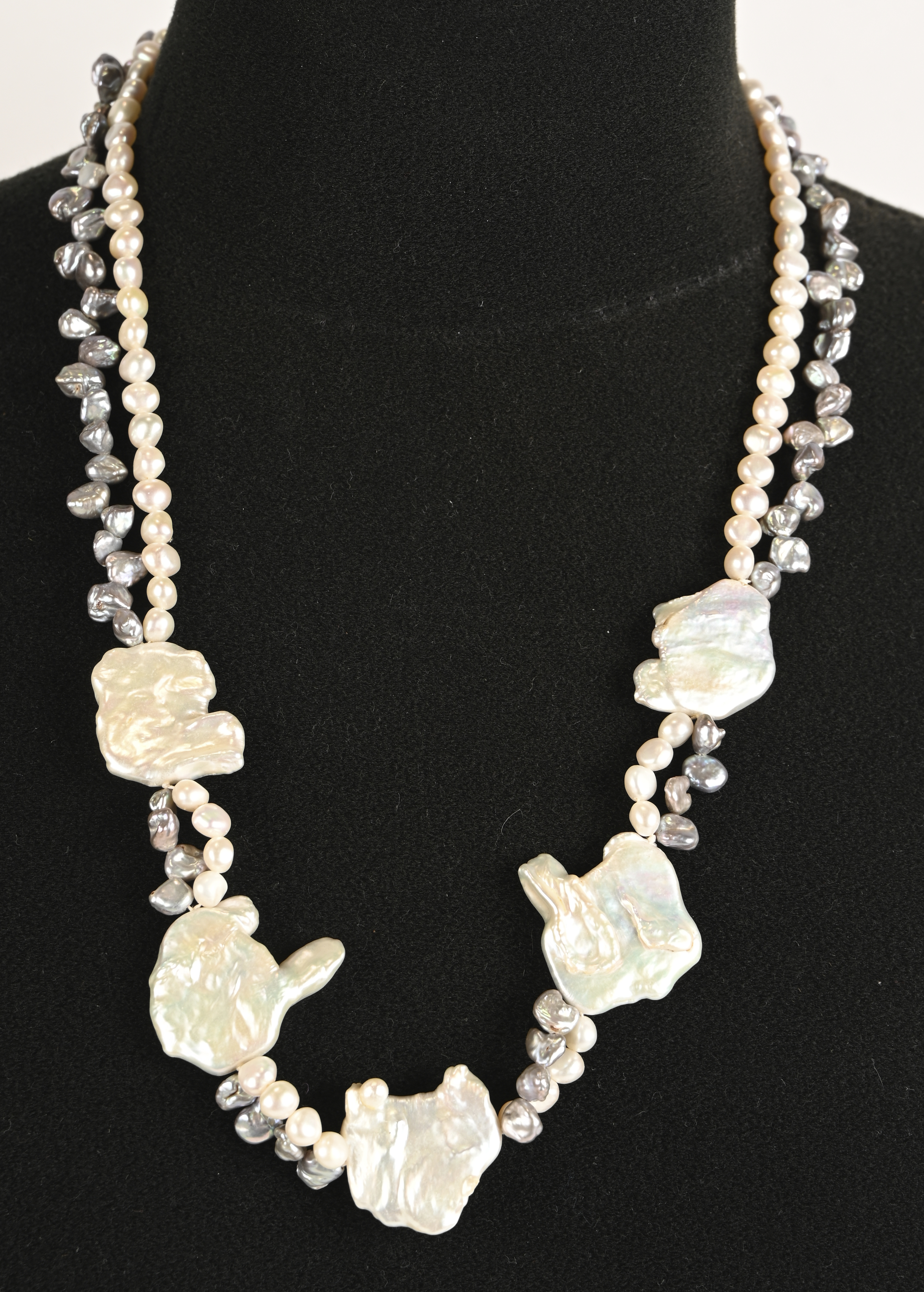 Een hallssnoer bezet met kleine witte en grijze parels en grote barokparels Een hallssnoer bezet met kleine witte en grijze parels en grote barokparels.