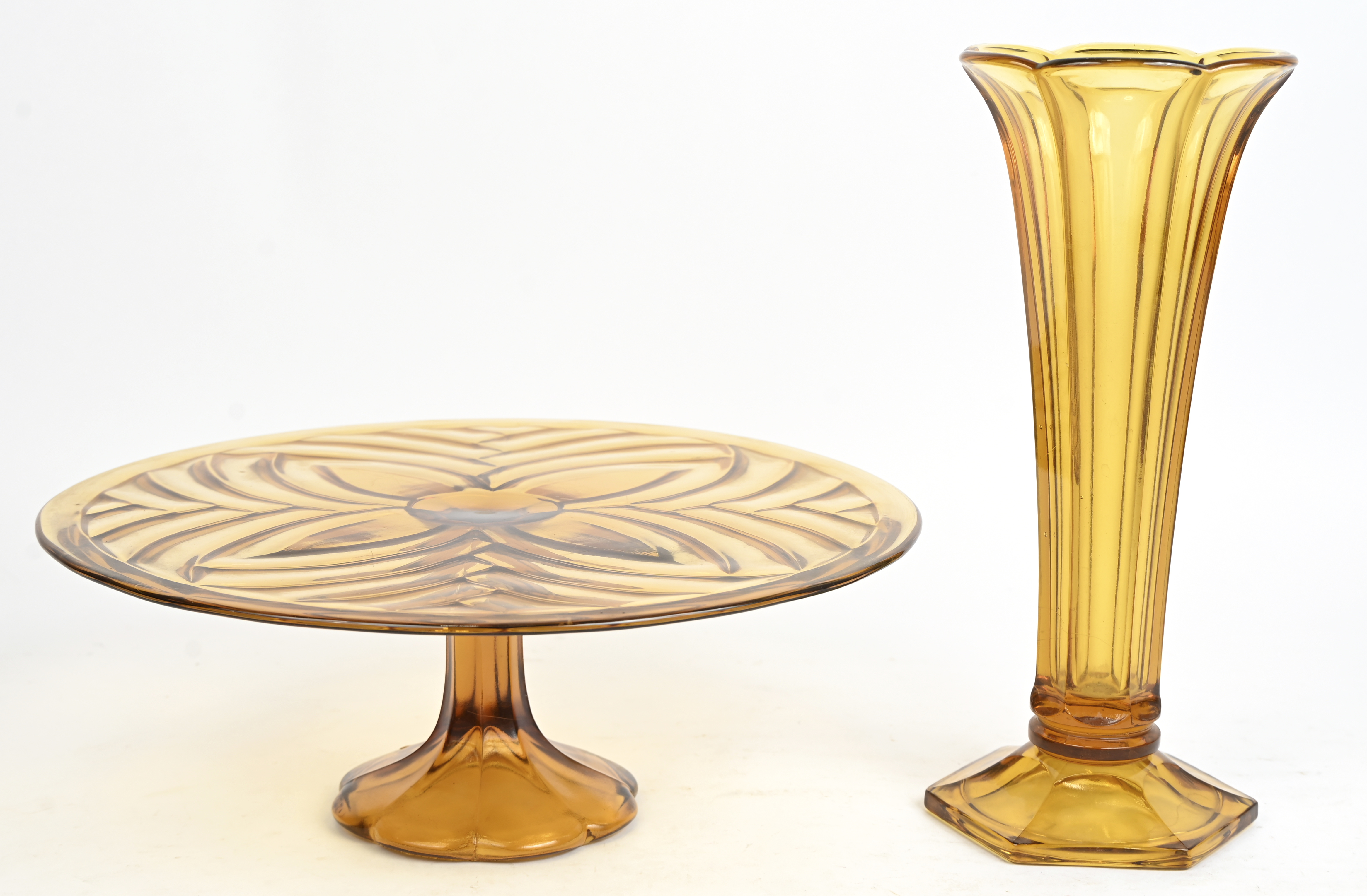 Een lot amberkleurig art-deco persglas, Luxval (Val Saint Lambert) bestaande uit een taartschaal en een vaas model ‘Americain’ Een lot amberkleurig art-deco persglas, Luxval (Val Saint Lambert) bestaande uit een taartschaal en een vaas model ‘Americain’.