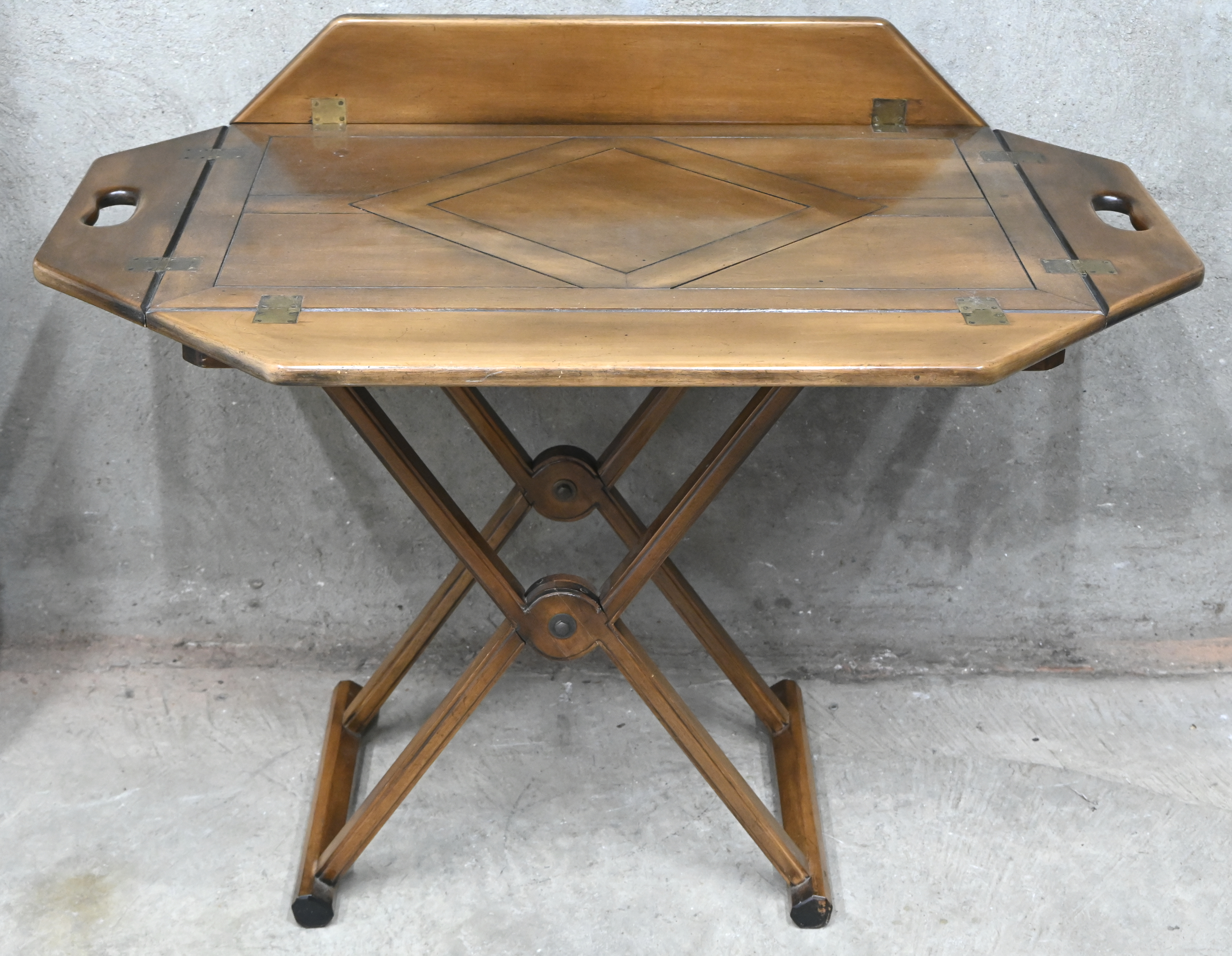 Een houten butlertray met opvouwbare staander en neerklapbare boord Een houten butlertray met opvouwbare staander en neerklapbare boord.