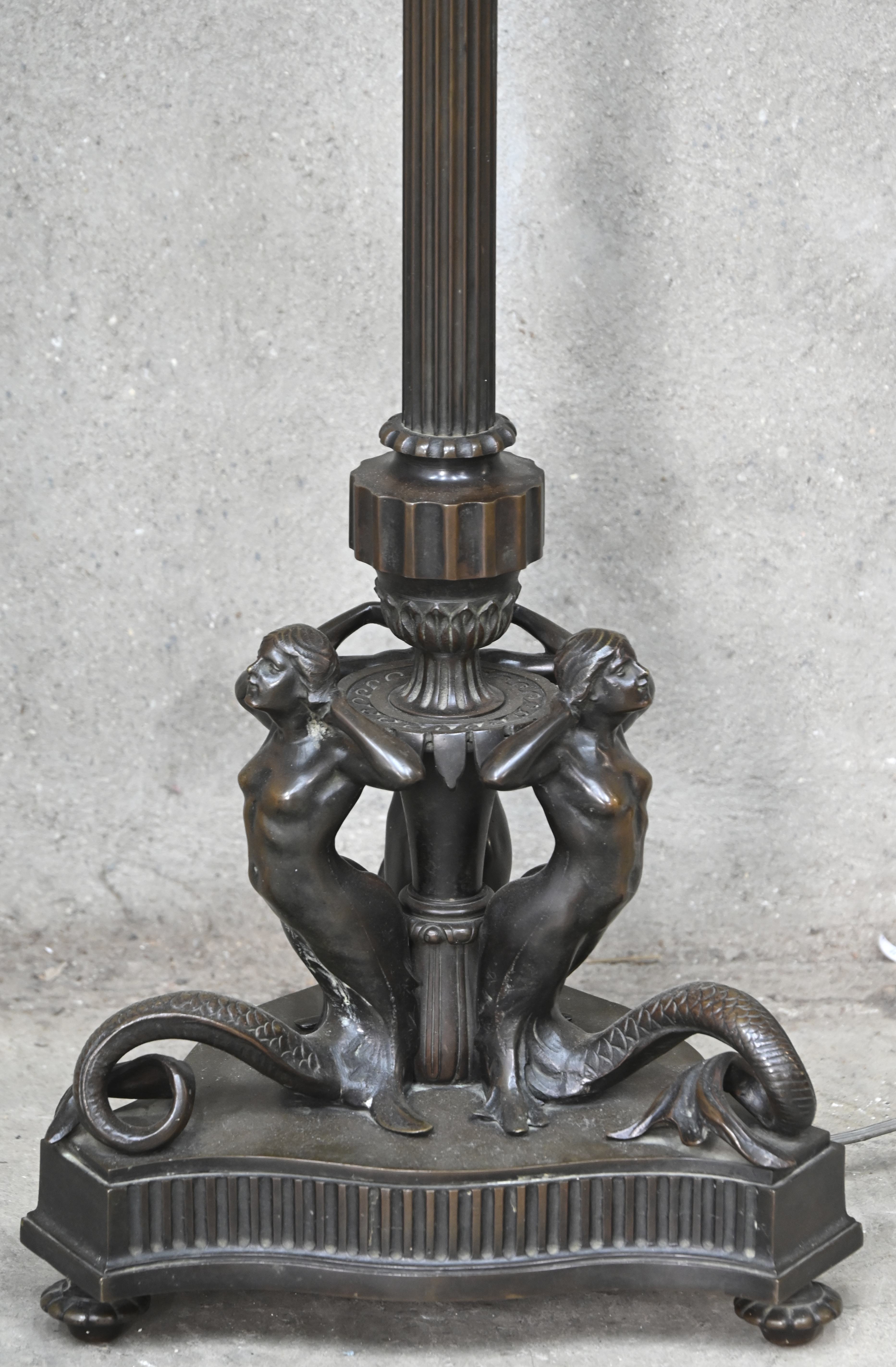 Een bronzen staanlamp met 3 zeemeerminnen op de voet. Lampenkap manco Een bronzen staanlamp met 3 zeemeerminnen op de voet. Lampenkap manco.