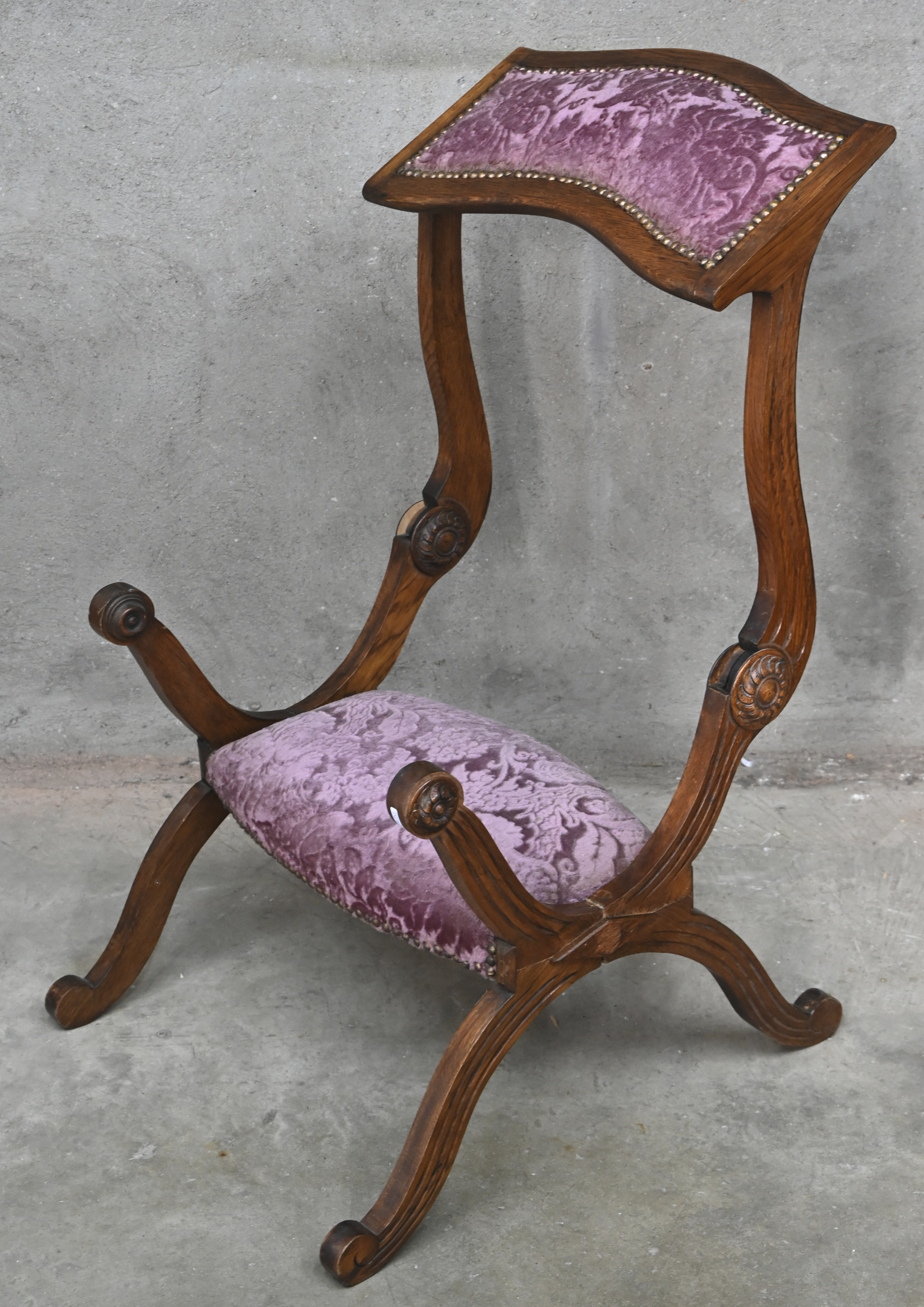 Een antieke massief eikenhouten bidstoel met gesculpteerde delen en roze velours bekleding Een antieke massief eikenhouten bidstoel met gesculpteerde delen en roze velours bekleding.