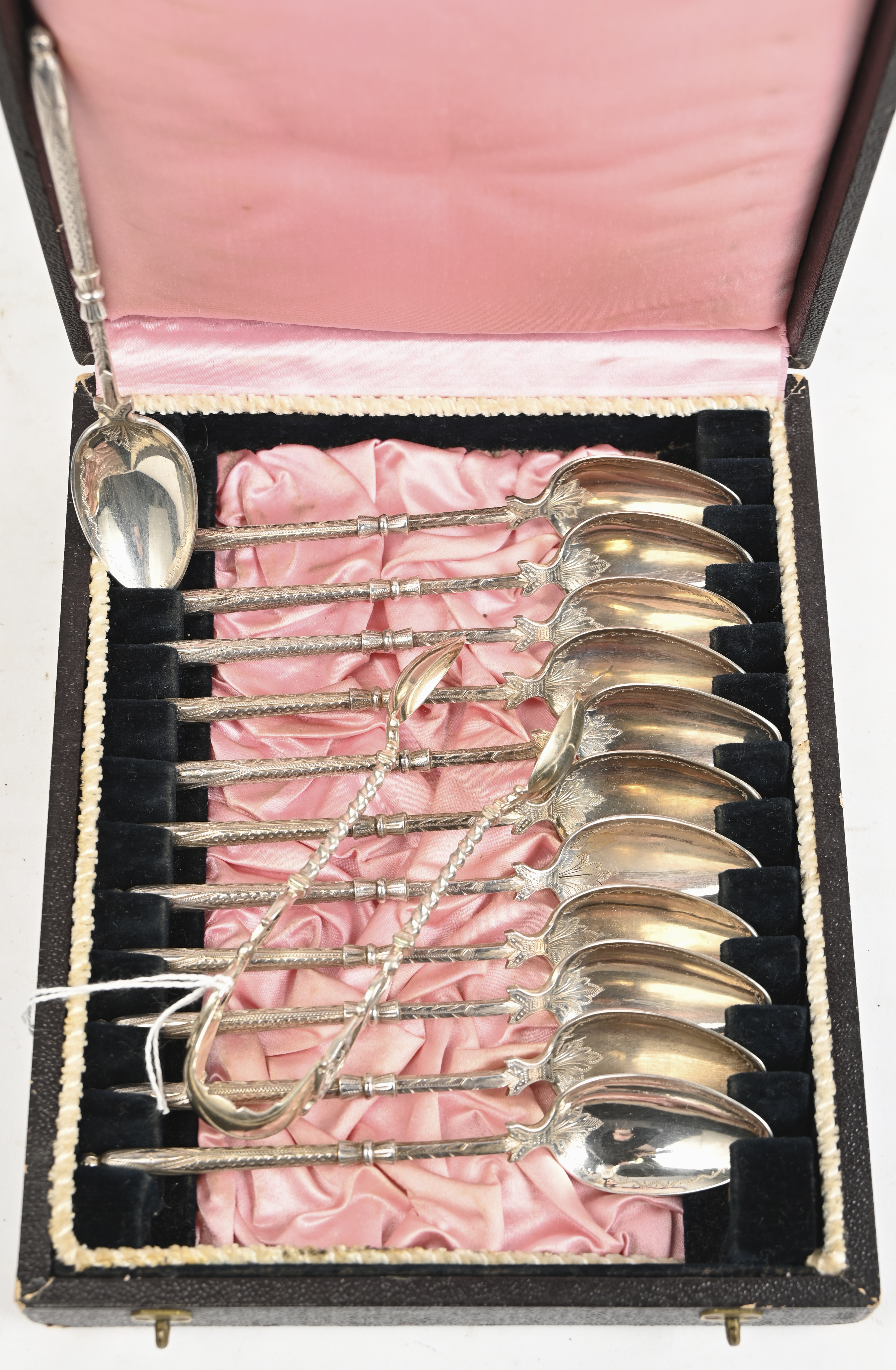 Een bestek cassette met 12 zilveren koffielepels (225 gram) met Frans export merk (1878 - 1973). Toegevoegd een zilveren suikertang (25 gram) met Duitse keuren, gemerkt 800 Een bestek cassette met 12 zilveren koffielepels (225 gram) met Frans export merk (1878 - 1973). Toegevoegd een zilveren suikertang (25 gram) met Duitse keuren, gemerkt 800.