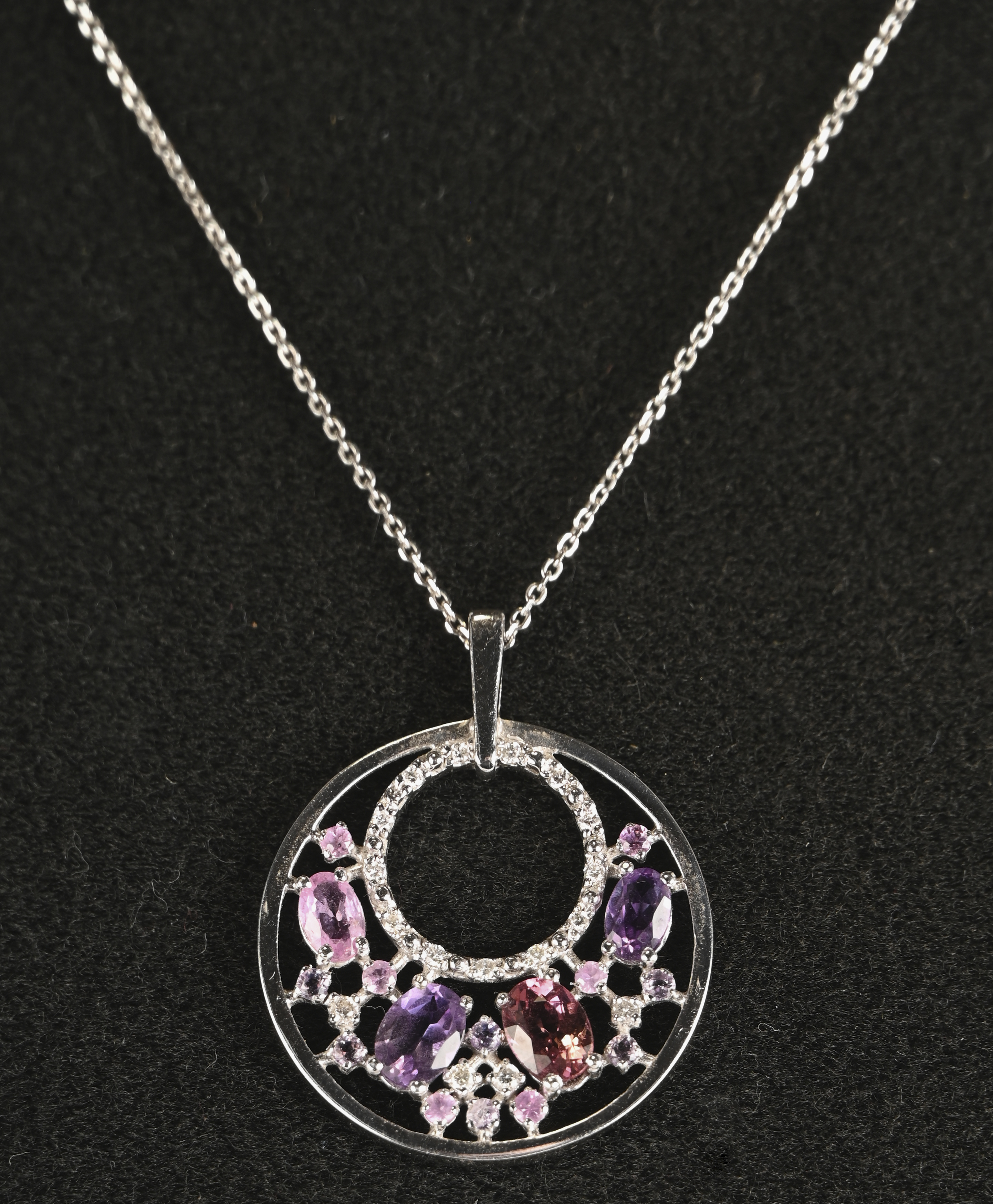 Een 18 kt witgouden ketting met hanger bezet met briljanten met een gezamenlijk gewicht van +- 0,20 ct. en amehist en tourmalijn met een gezamenlijk gewicht van +- 1,50 ct Een 18 kt witgouden ketting met hanger bezet met briljanten met een gezamenlijk gewicht van +- 0,20 ct. en amehist en tourmalijn met een gezamenlijk gewicht van +- 1,50 ct.