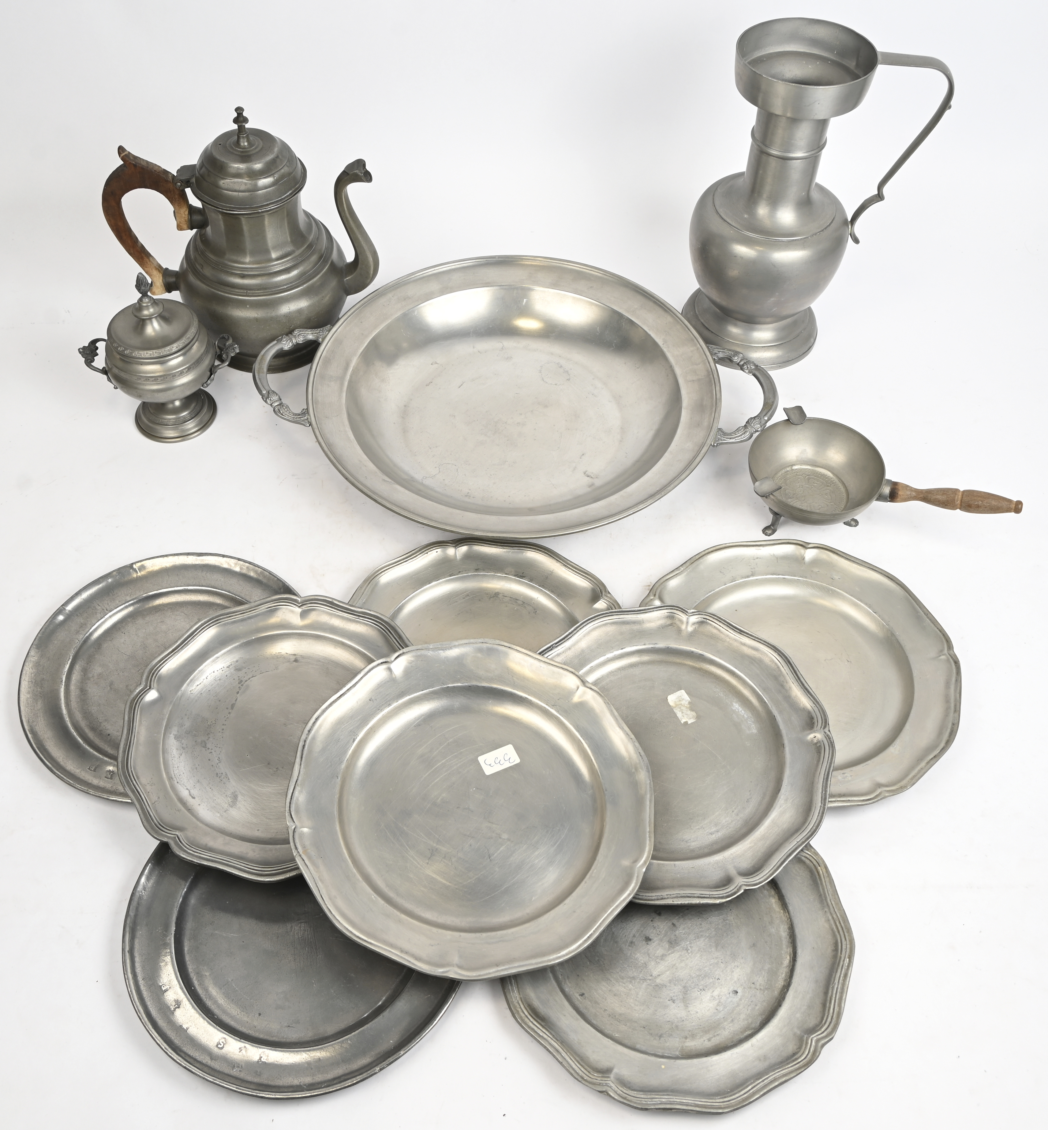 Een uitgebreid lot tin. Bestaande uit 8 borden, kruik met handvat, theepot met houten handvat, suikerpotje, asbak met handvat en drie poten, grote schaal met handvaten en poten Een uitgebreid lot tin. Bestaande uit 8 borden, kruik met handvat, theepot met houten handvat, suikerpotje, asbak met handvat en drie poten, grote schaal met handvaten en poten.