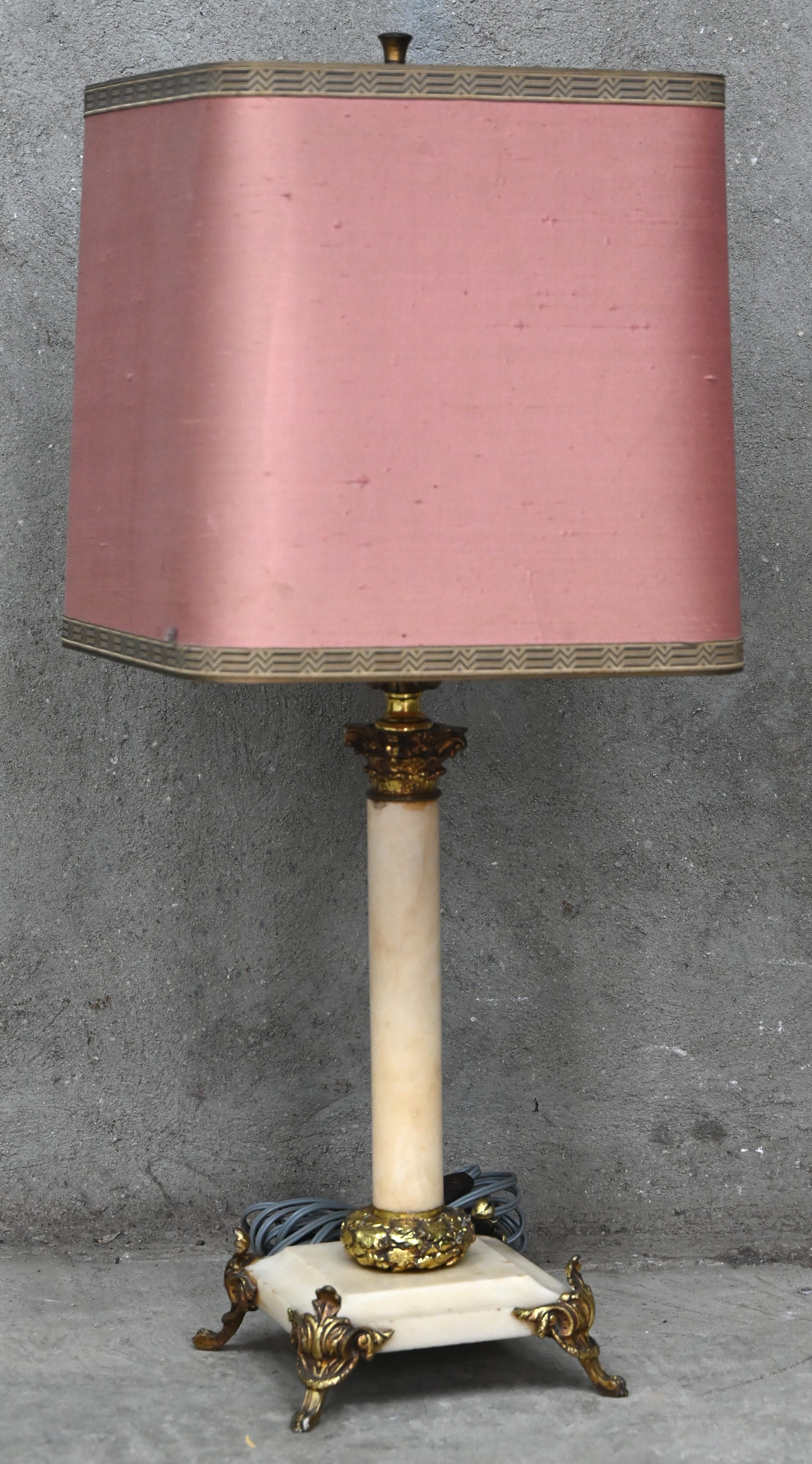 Een klassieke tafellamp, albasten voet met messing delen en roze kap Een klassieke tafellamp, albasten voet met messing delen en roze kap.