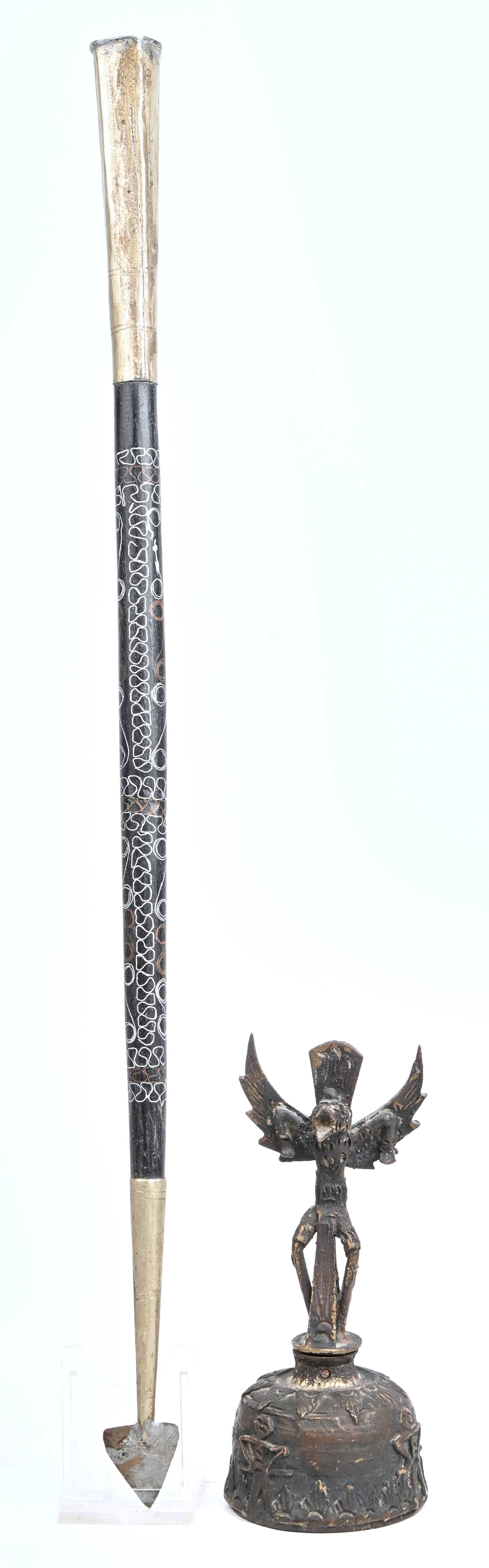 Twee etnische objecten, een bronzen belletje en een baton Twee etnische objecten, een bronzen belletje en een baton.