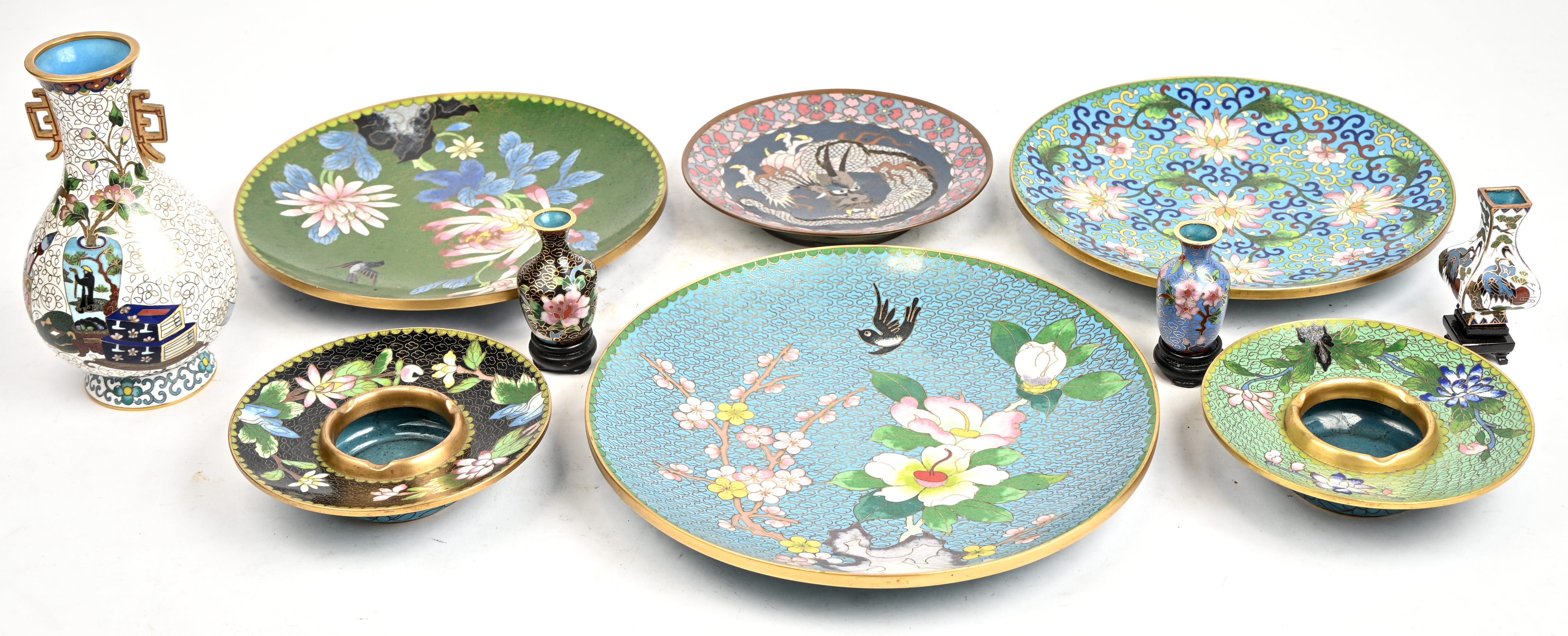 Een lot cloisoné bestaande uit 4 bordjes, 2 asbakken en 4 vaasjes waarvan de 3 kleinste op houten sokkeltje Een lot cloisoné bestaande uit 4 bordjes, 2 asbakken en 4 vaasjes waarvan de 3 kleinste op houten sokkeltje.