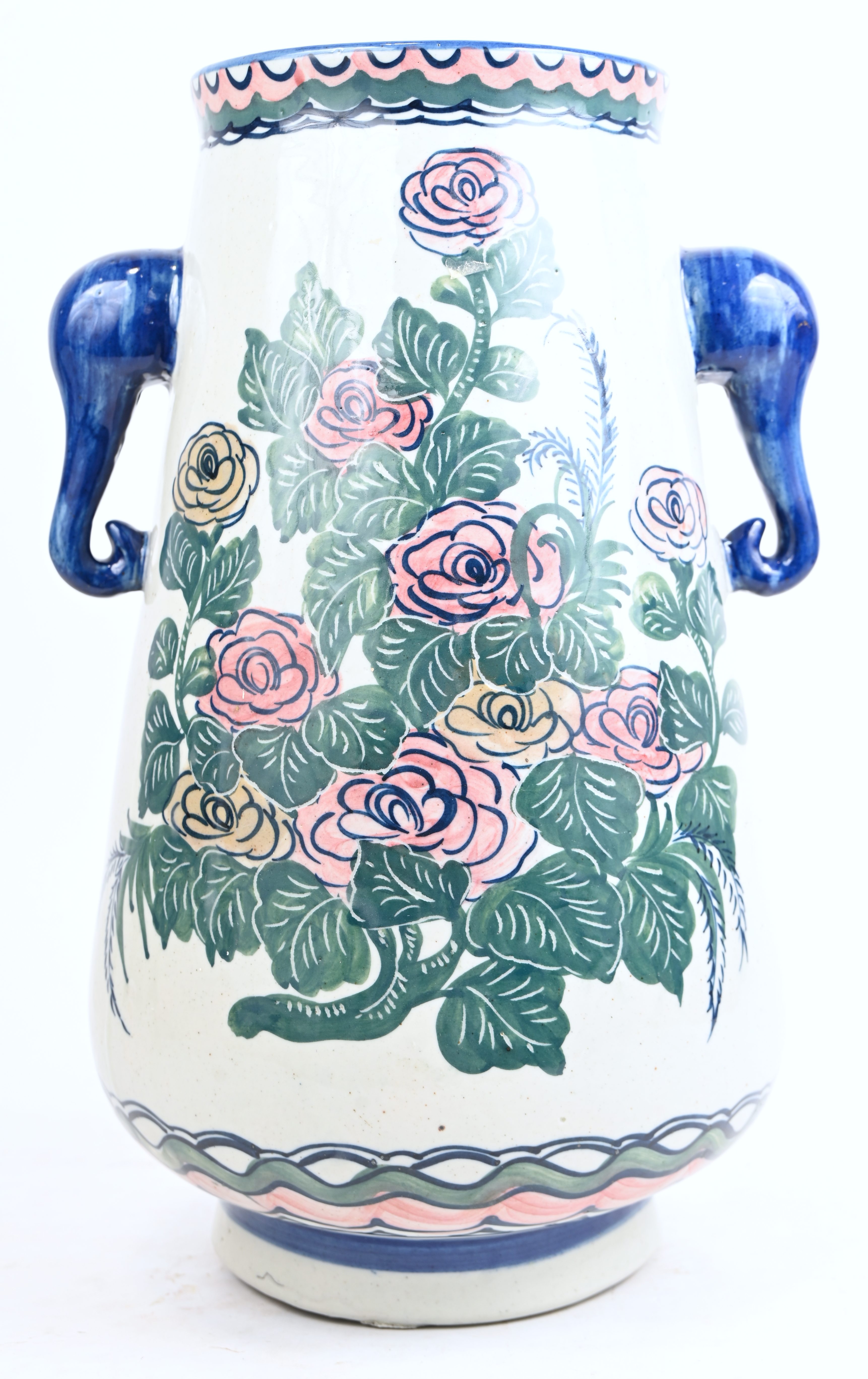 Een aardewerken vaas met decor van bloemen en handvaten in de vorm van gestyleerde kobalt-kleurige olifanten Een aardewerken vaas met decor van bloemen en handvaten in de vorm van gestyleerde kobalt-kleurige olifanten.