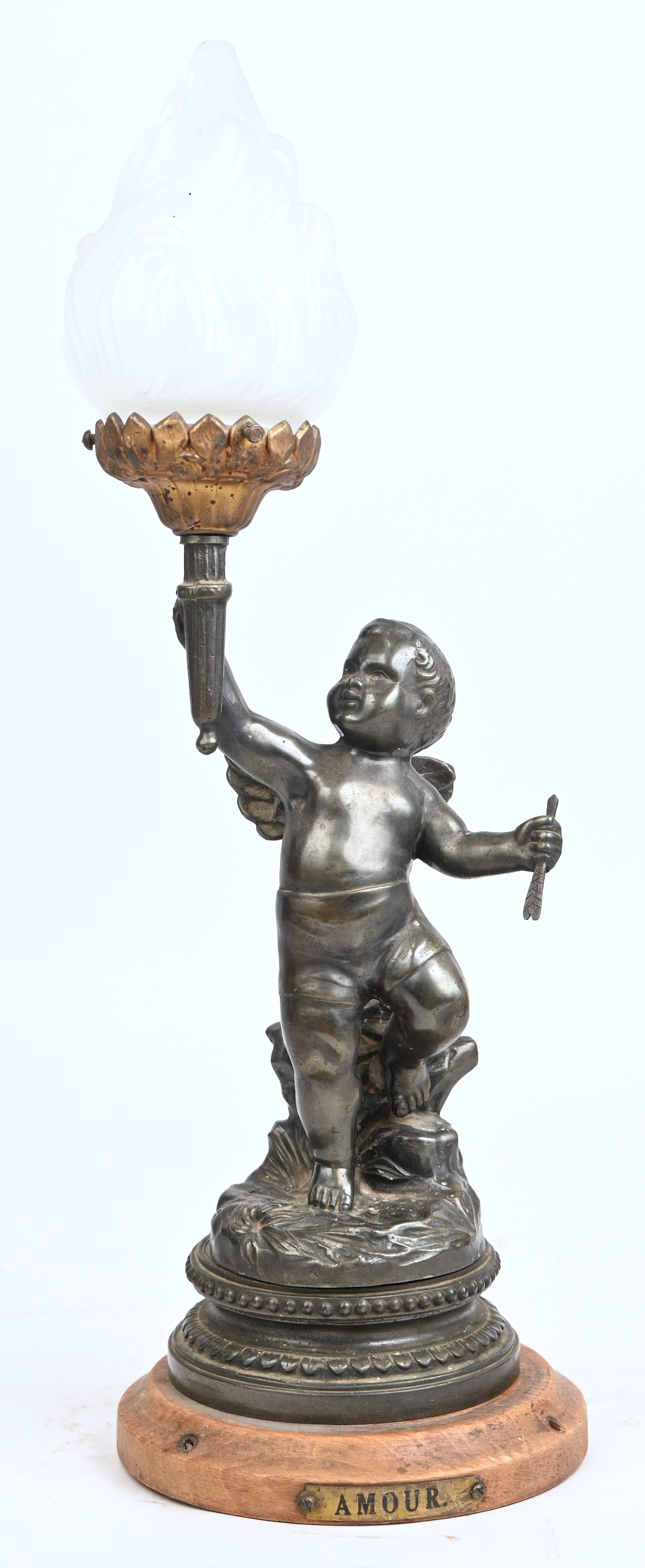 Een lampje in de vorm van een putti met een fakkel in de hand. Te herbekabelen. Van gepatineerd metaal en opaline glas Een lampje in de vorm van een putti met een fakkel in de hand. Te herbekabelen. Van gepatineerd metaal en opaline glas.