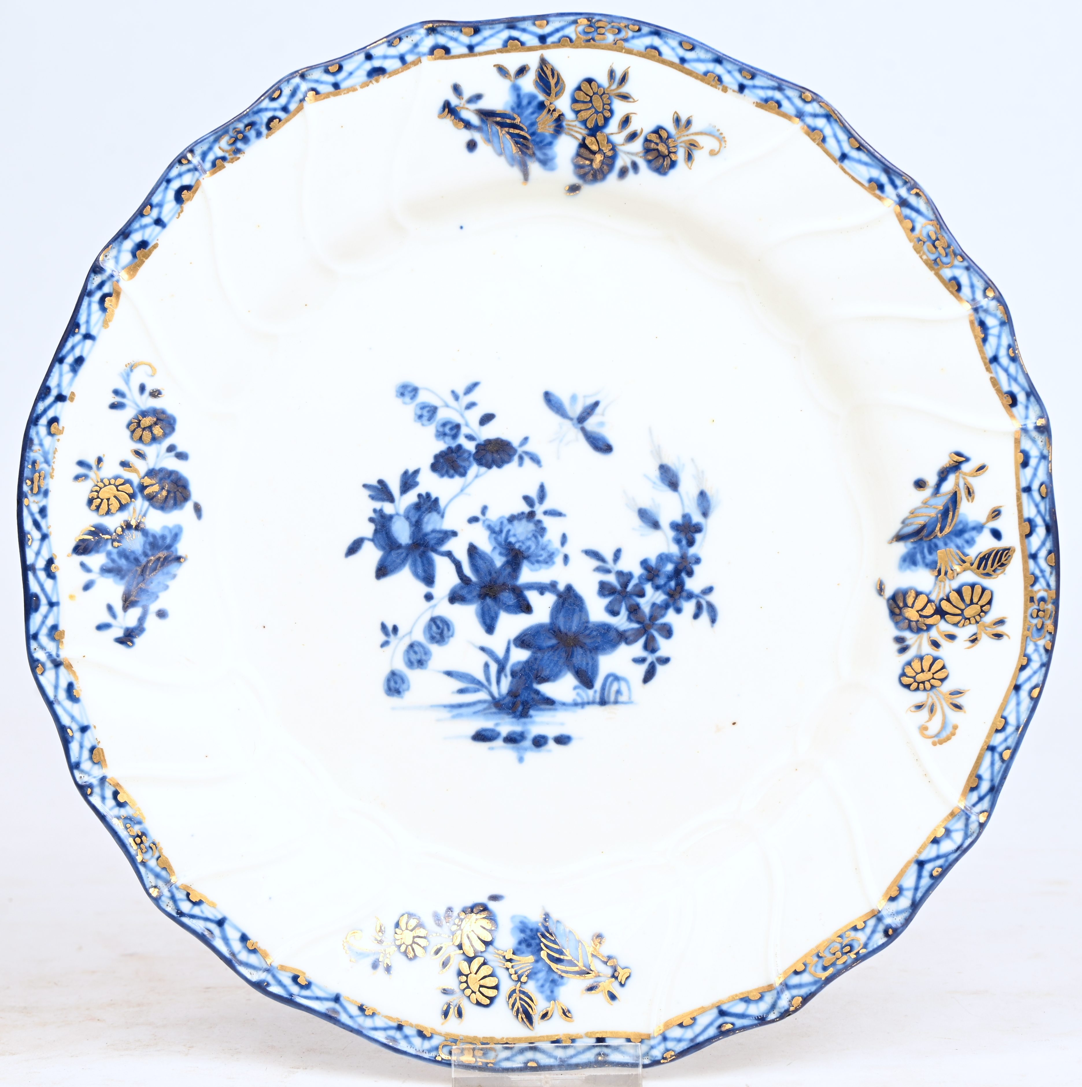 Bord met een blauw “A la mouche”-decor, gehoogd met goud. Vier boeketten op de vleugel. Getorste ribben, gechantourneerde rand. Onderaan gemerkt met de toren in goud. Doornik, XVIIIde eeuw Bord met een blauw “A la mouche”-decor, gehoogd met goud. Vier boeketten op de vleugel. Getorste ribben, gechantourneerde rand. Onderaan gemerkt met de toren in goud. Doornik, XVIIIde eeuw.