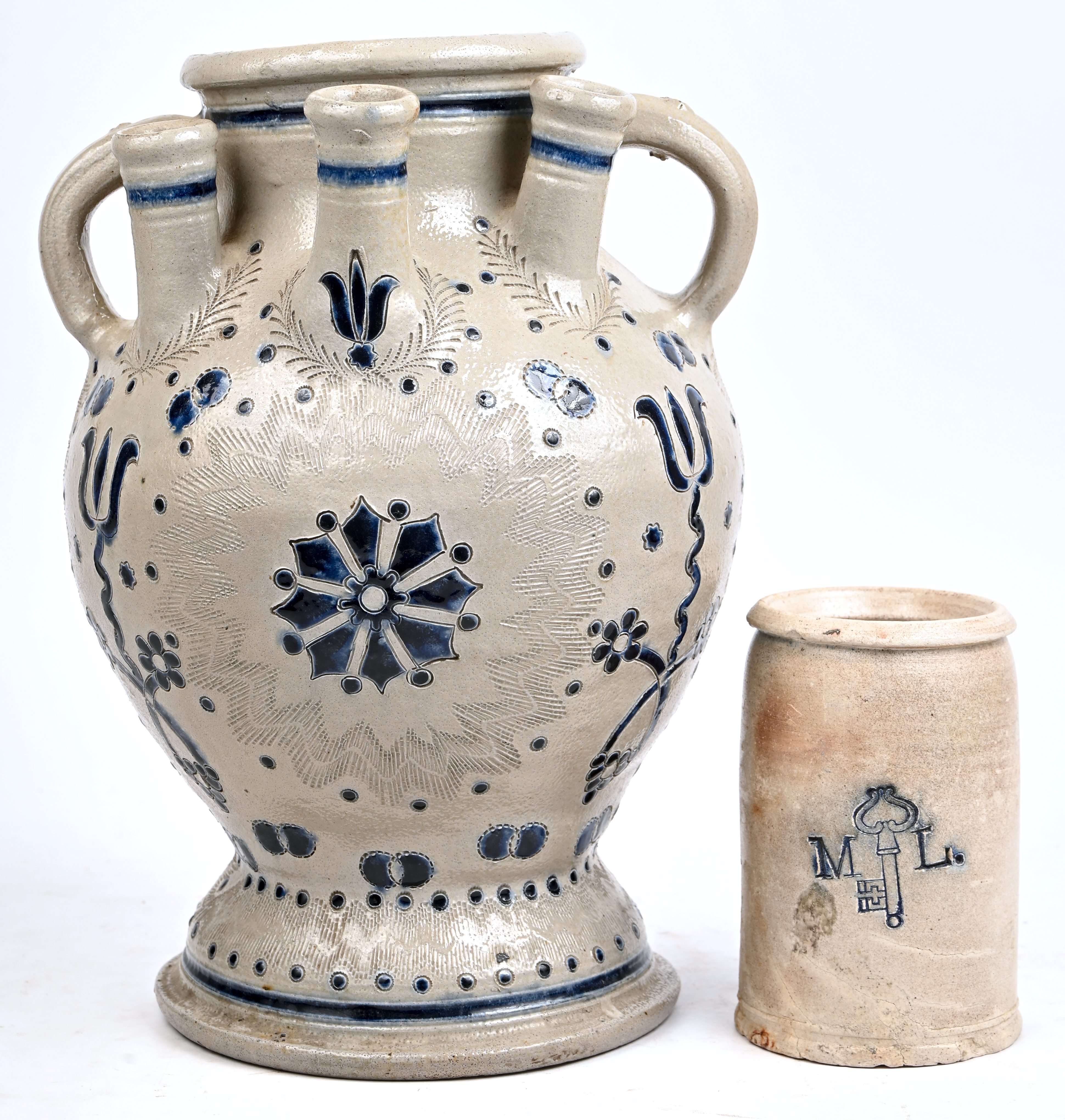 Een tulpenvaas van Westerwald aardewerk. Toegevoegd een oude mosterdpot, gemerkt M.L. en een sleutel Een tulpenvaas van Westerwald aardewerk. Toegevoegd een oude mosterdpot, gemerkt M.L. en een sleutel.