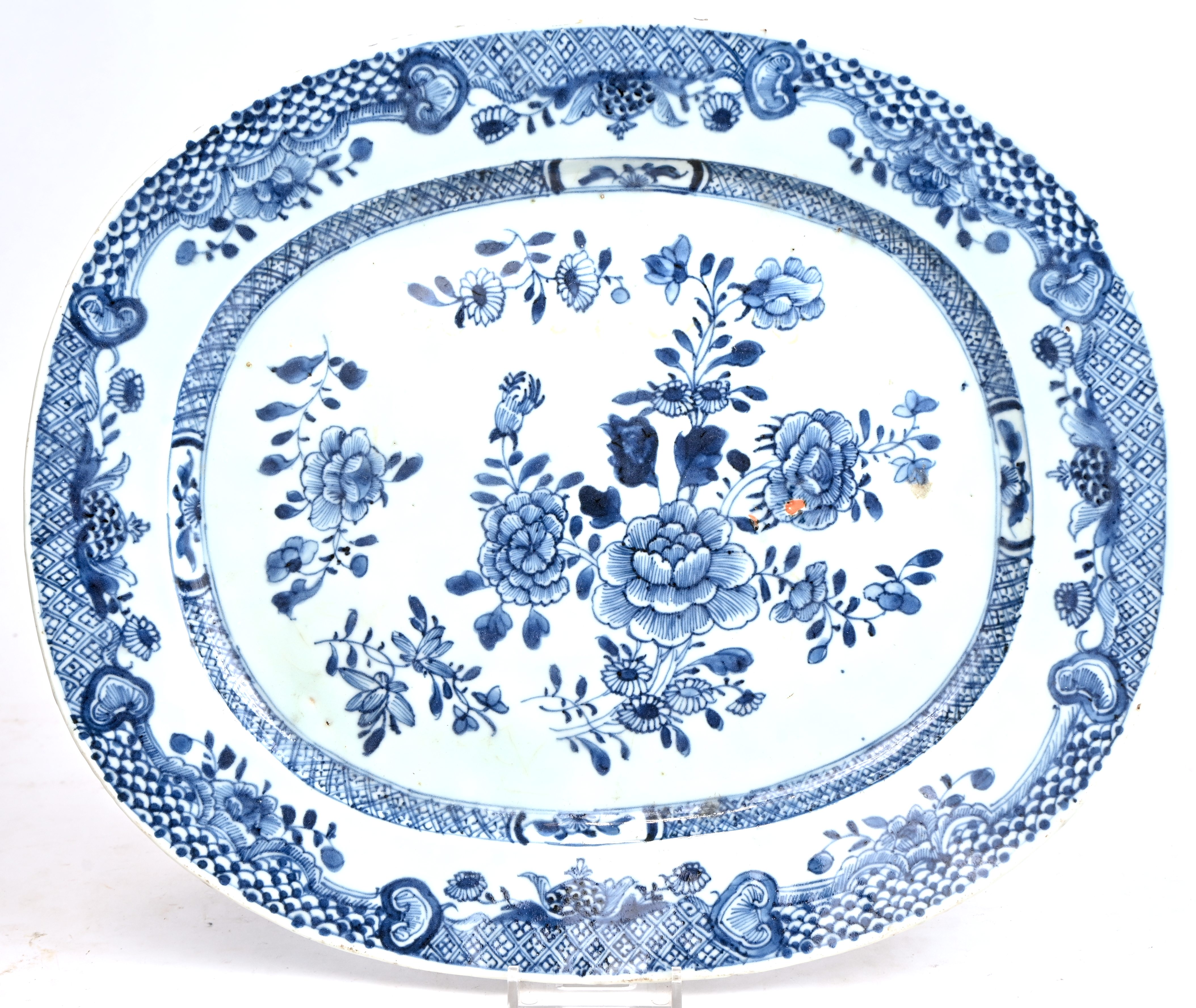 Een langwerpige schotel van blauw en wit Chinees porselein, versierd met bloemen op het plat en met een Lodewijk XV-fries op de vleugel. XIXde eeuw Een langwerpige schotel van blauw en wit Chinees porselein, versierd met bloemen op het plat en met een Lodewijk XV-fries op de vleugel. XIXde eeuw.