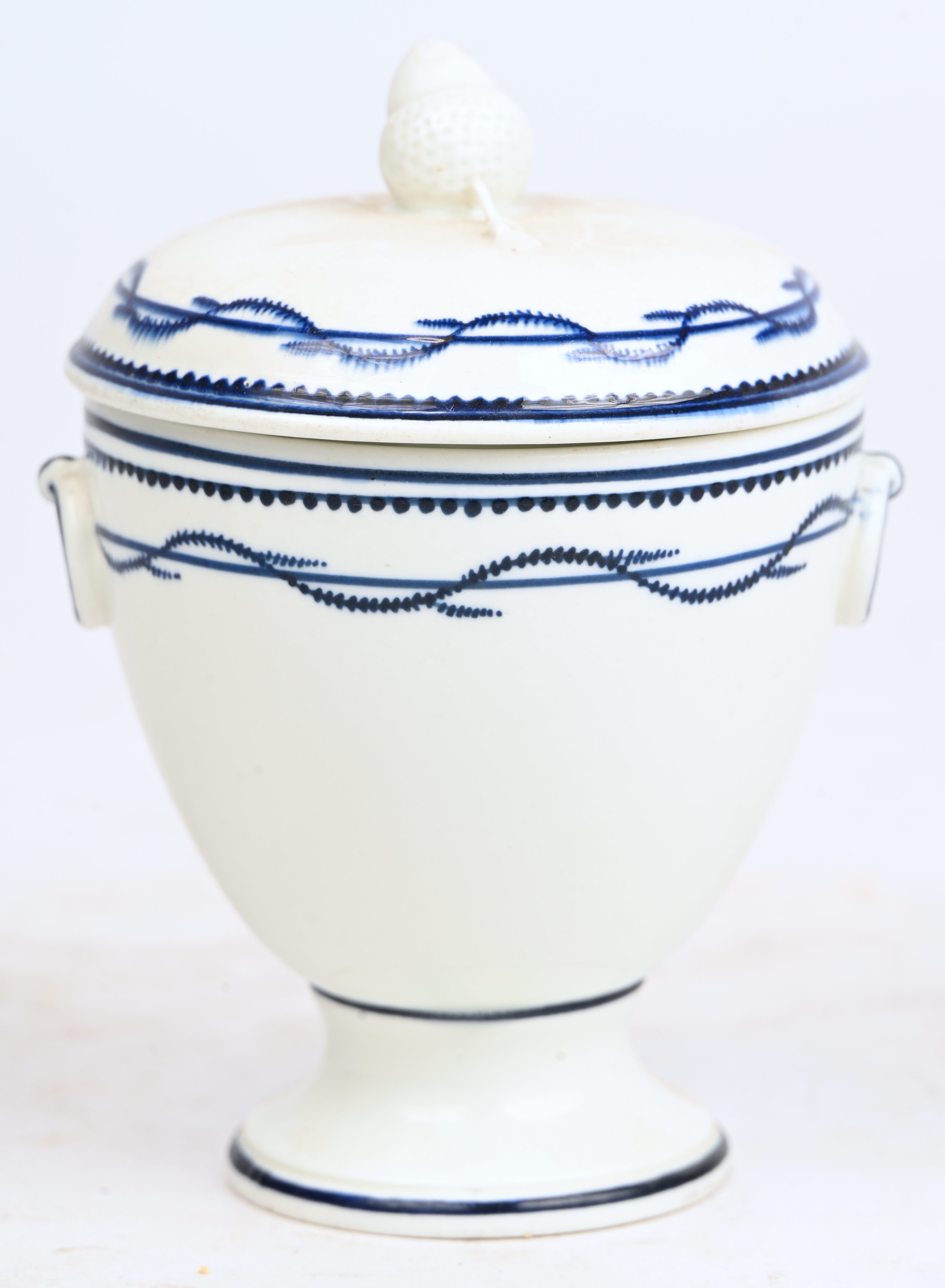 Roompotje op voet van zachte pasta met een blauw “à la chenille”-decor. Twee ringen in reliëf op de schouder. Dekselknop in de vorm van een eikel. Doornik, tijdperk Empire Roompotje op voet van zachte pasta met een blauw “à la chenille”-decor. Twee ringen in reliëf op de schouder. Dekselknop in de vorm van een eikel. Doornik, tijdperk Empire.