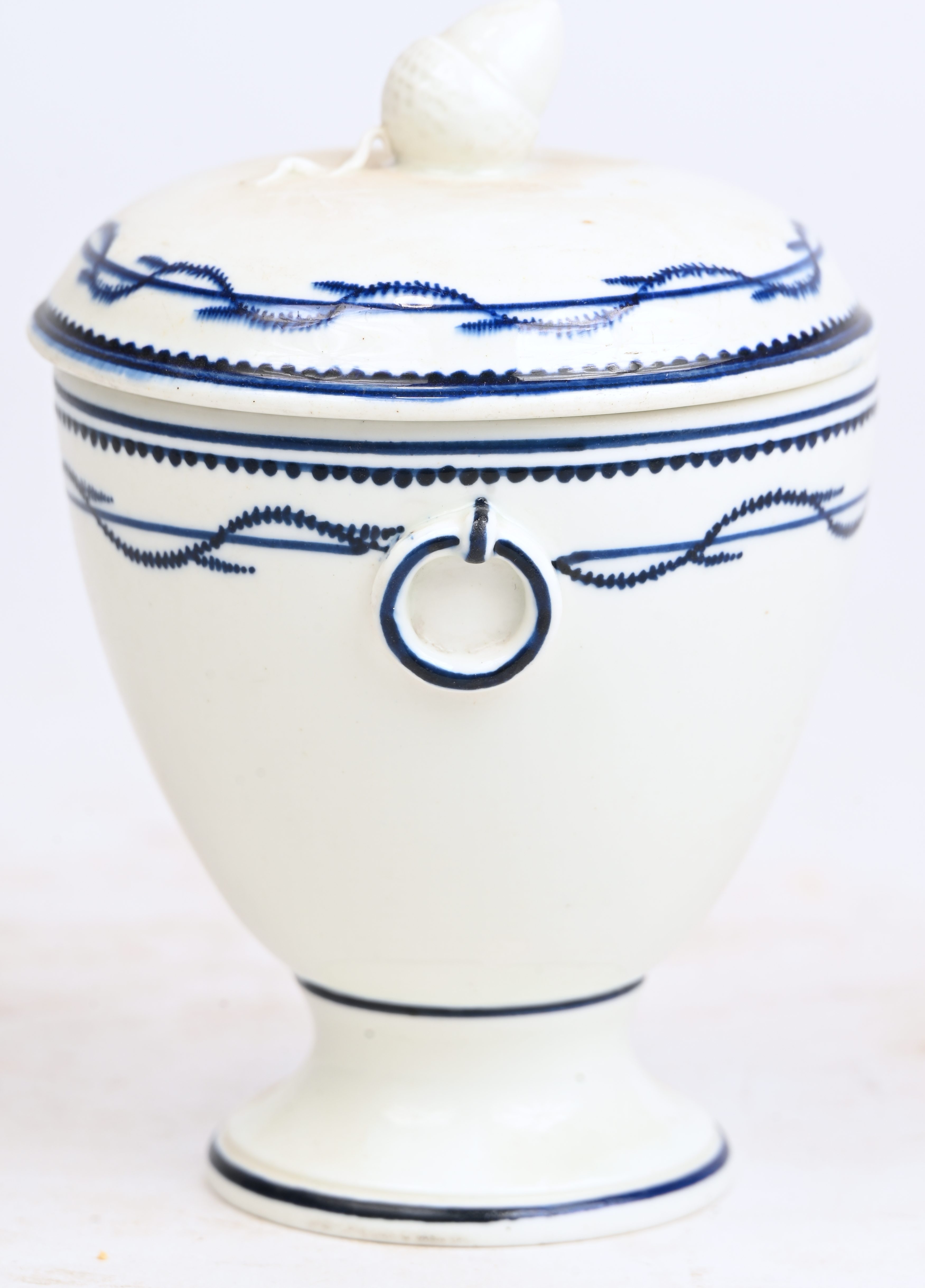 Roompotje op voet van zachte pasta met een blauw “à la chenille”-decor. Twee ringen in reliëf op de schouder. Dekselknop in de vorm van een eikel. Doornik, tijdperk Empire Roompotje op voet van zachte pasta met een blauw “à la chenille”-decor. Twee ringen in reliëf op de schouder. Dekselknop in de vorm van een eikel. Doornik, tijdperk Empire.