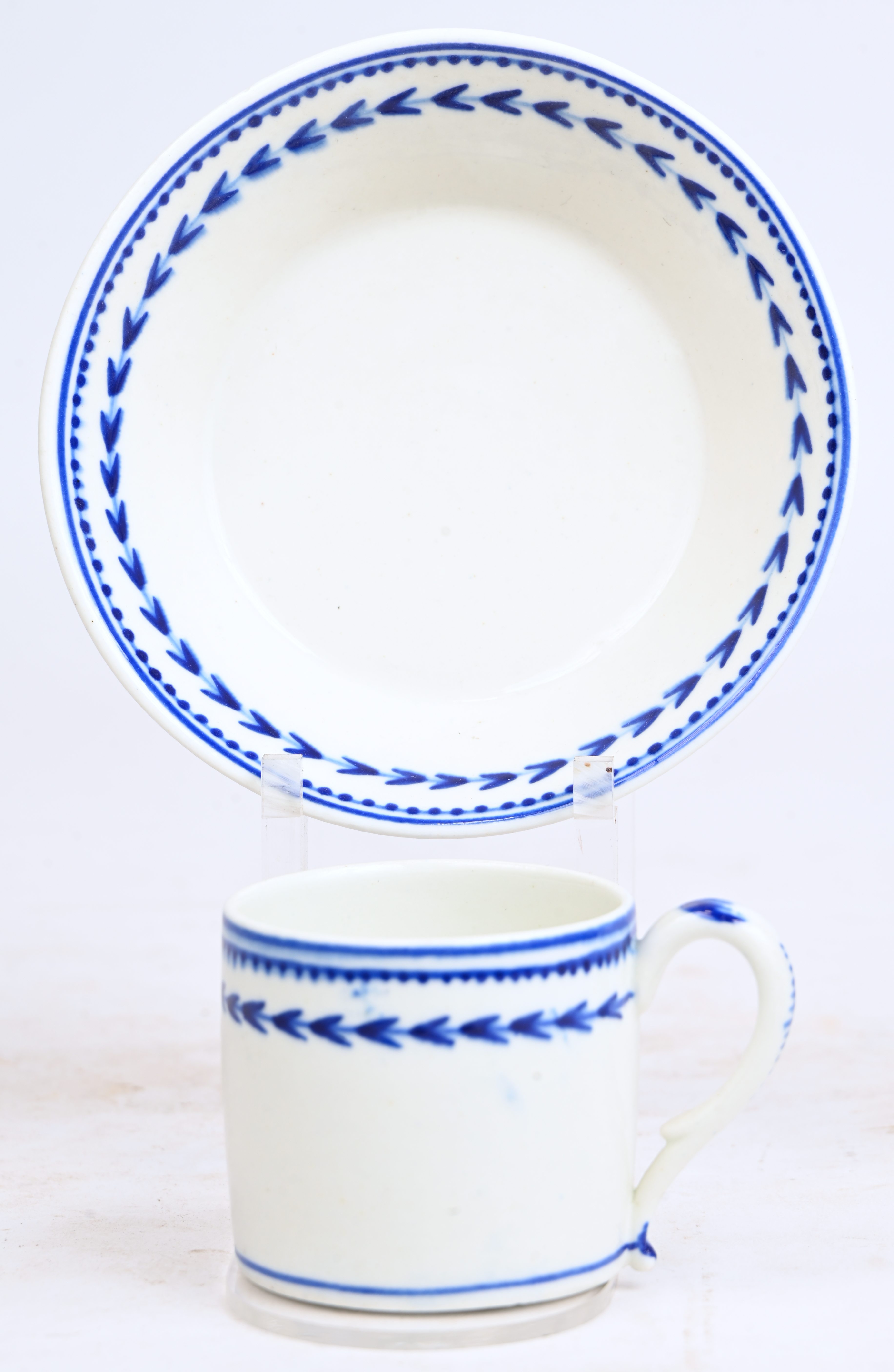 Een recht kopje en schoteltje met hoge rand, z.g. trembleuse van zachte pasta met een blauw decor “à l’épi”. Doornik, XIXde eeuw Een recht kopje en schoteltje met hoge rand, z.g. trembleuse van zachte pasta met een blauw decor “à l’épi”. Doornik, XIXde eeuw.