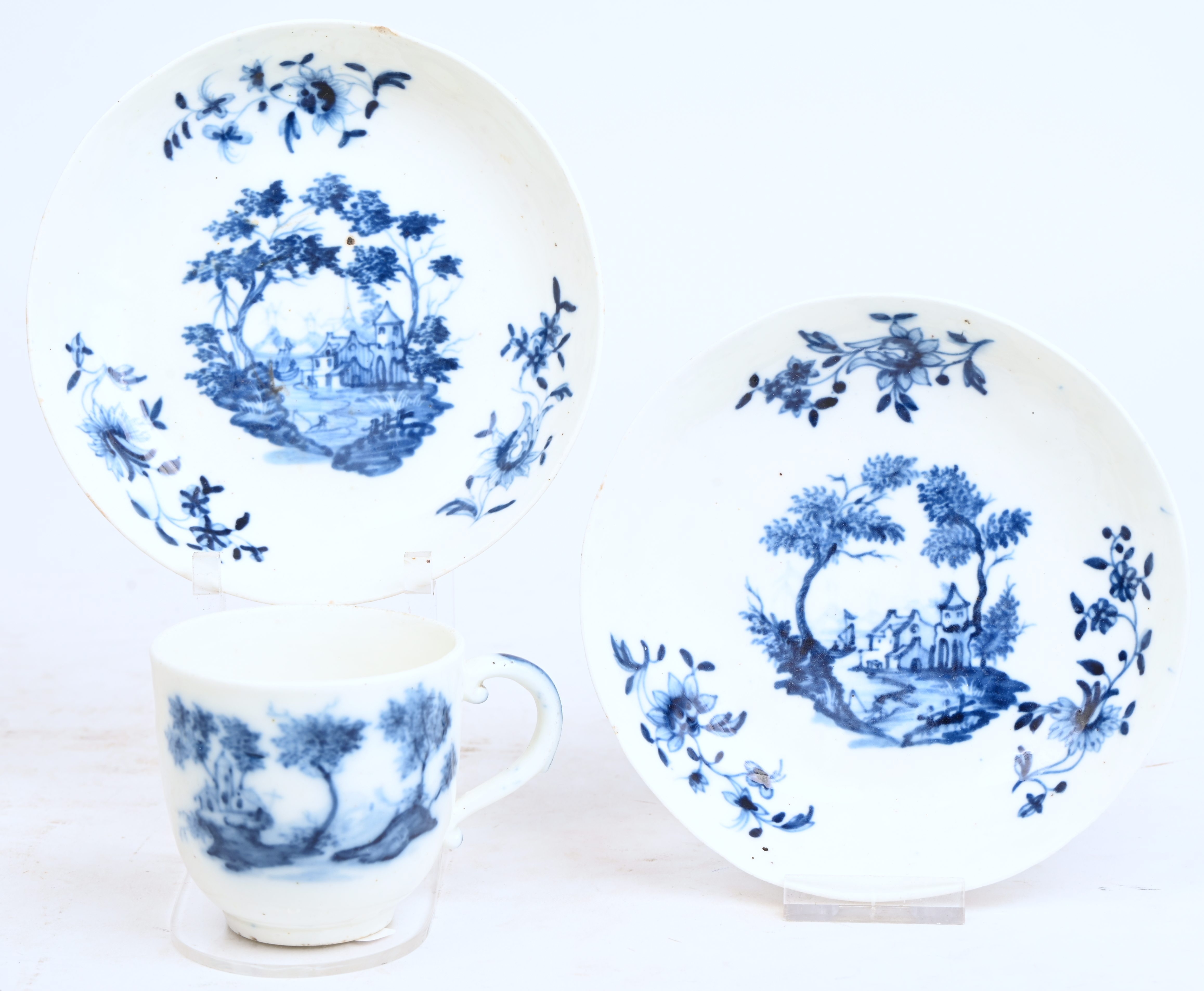 Twee schoteltjes en een kopje met kolfvormig oor. Blauw decor met “Hollands landschap” en drie boeketten op de vleugel. Doornik, XIXde eeuw Twee schoteltjes en een kopje met kolfvormig oor. Blauw decor met “Hollands landschap” en drie boeketten op de vleugel. Doornik, XIXde eeuw.