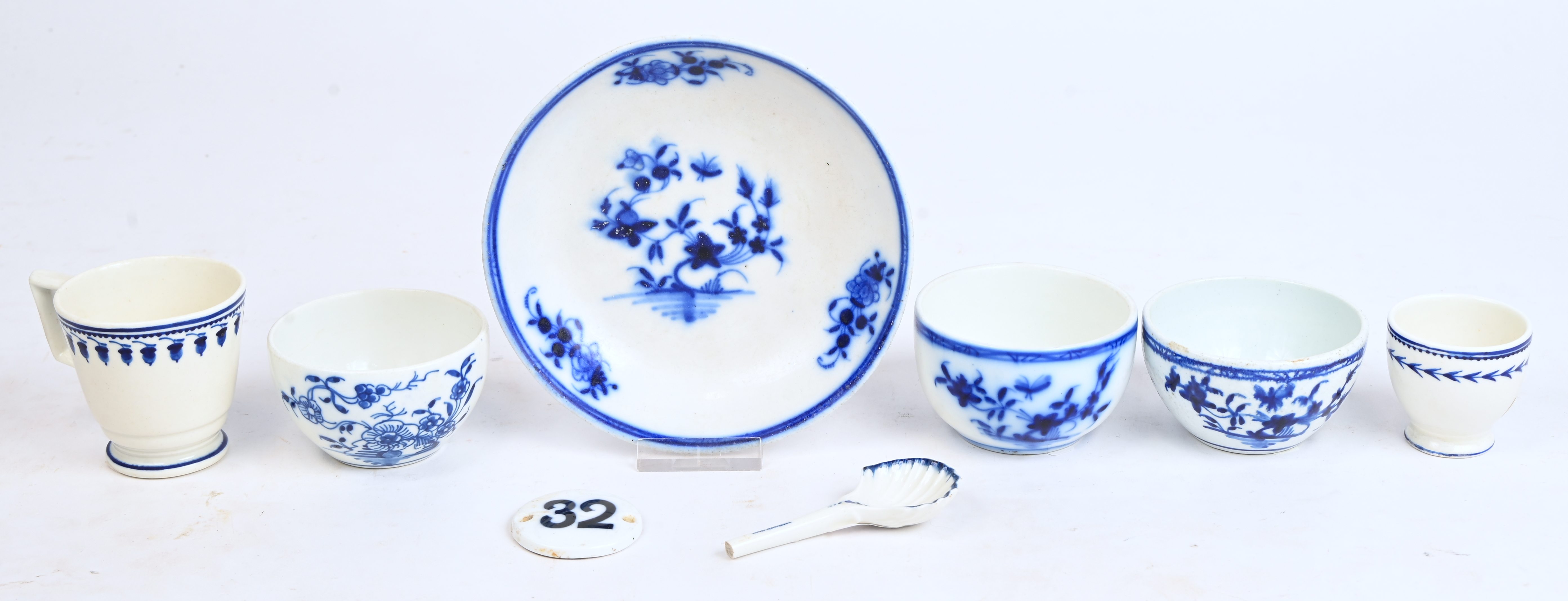 Drie pochons en een schoteltje met blauw “Ronda” en “A la mouche”-decor, een obconisch kopje met recht oor met blauw “aux glands”-decor gemelrt B, een deurnummer “32”, een eierdopje met een guirlande “à l’épi” en een schelpvormig suikerschepje met gebroken steel. Doornik, XIXde eeuw Drie pochons en een schoteltje met blauw “Ronda” en “A la mouche”-decor, een obconisch kopje met recht oor met blauw “aux glands”-decor gemelrt B, een deurnummer “32”, een eierdopje met een guirlande “à l’épi” en een schelpvormig suikerschepje met gebroken steel. Doornik, XIXde eeuw.