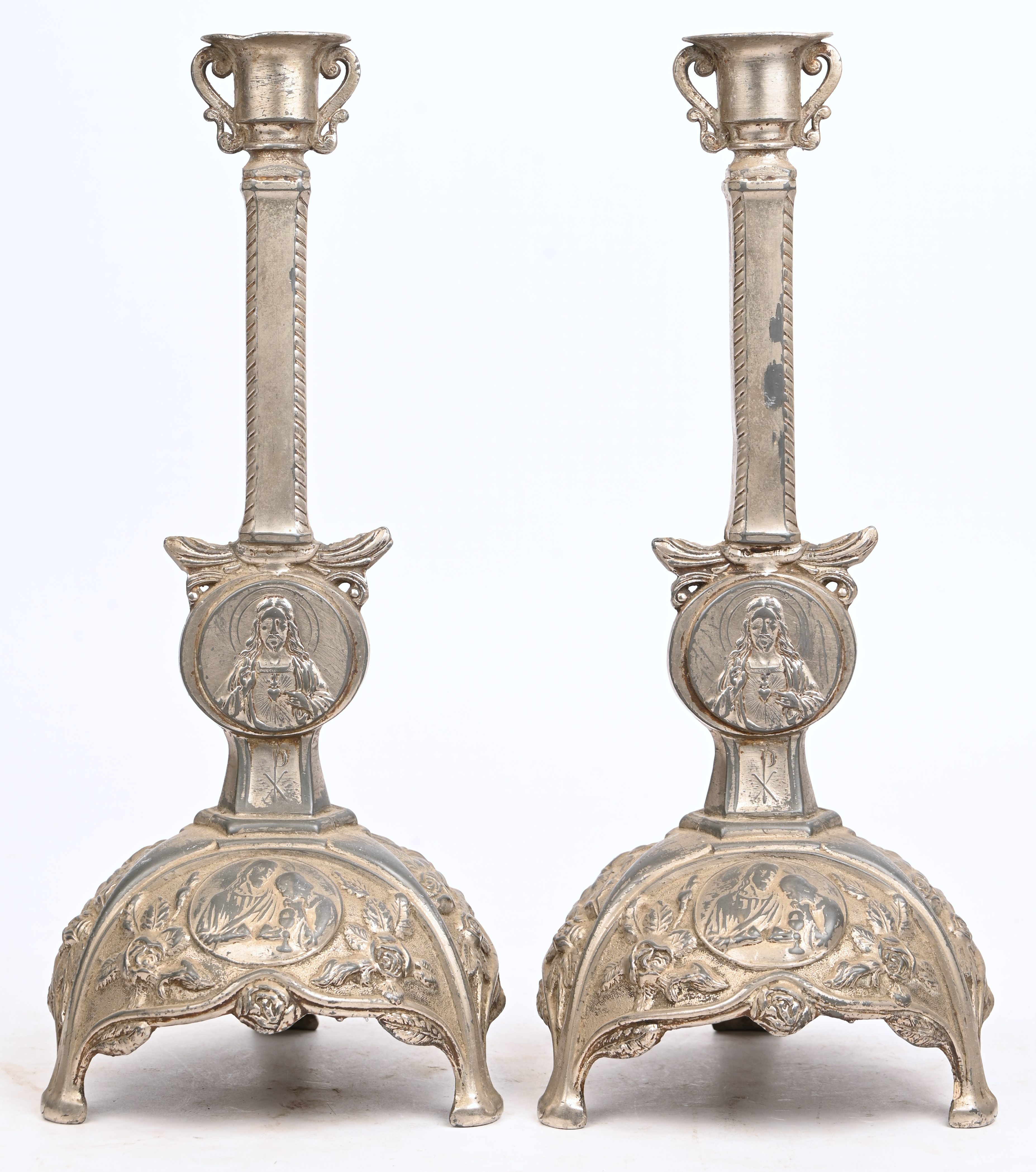 Een set verzilverd metalen kandelaars met religieus thema Een set verzilverd metalen kandelaars met religieus thema.