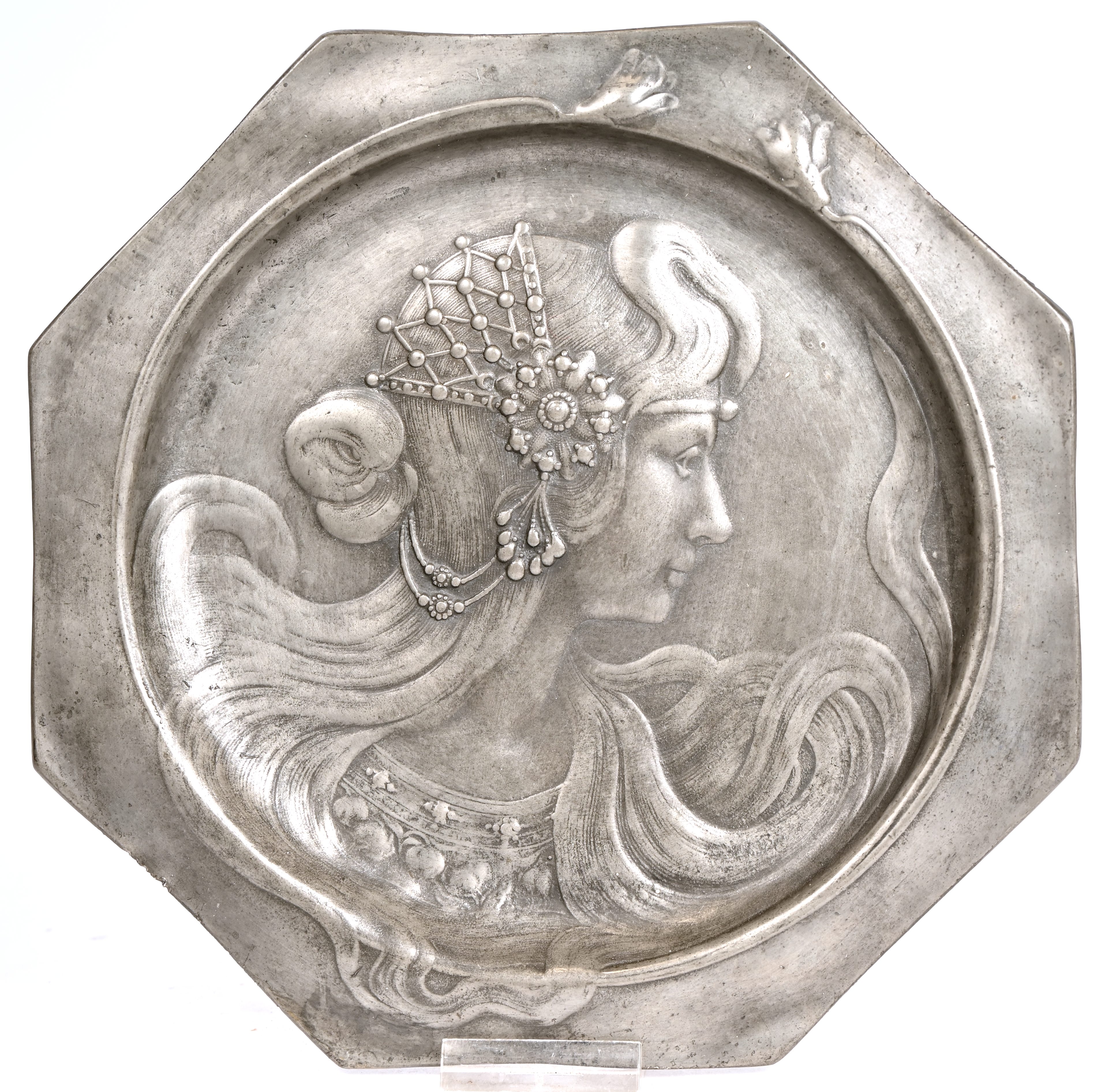 Een tinnen art-nouveau bord met de beeltenis van een jongedame Een tinnen art-nouveau bord met de beeltenis van een jongedame. 475 gram